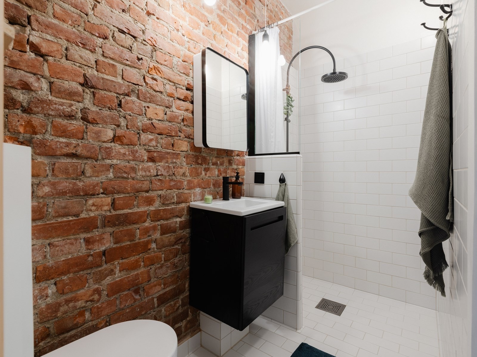 Badet har en helt unik løsning med synlig original murvegg mot hvite fliser Galleribilde