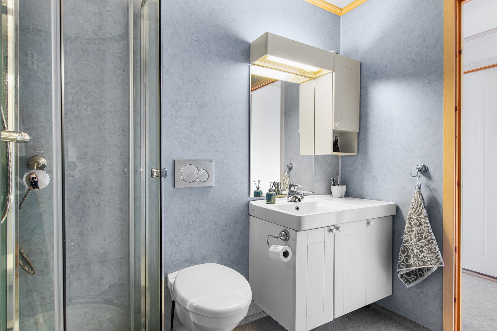 Badet er innredet med vegghengt baderomsinnredning med servanttopp, wc, dusjkabinett og opplegg for vaskemaskin. Galleribilde