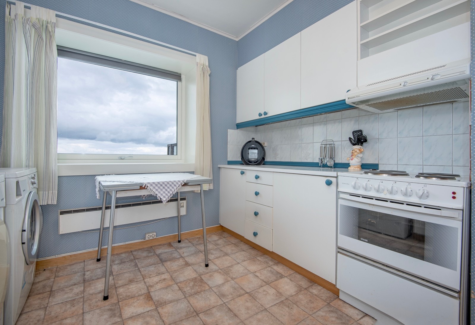 Eldre innredningen med hvite fronter og laminat benkeplate, det er gode arbeidsflater for matlaging. Galleribilde