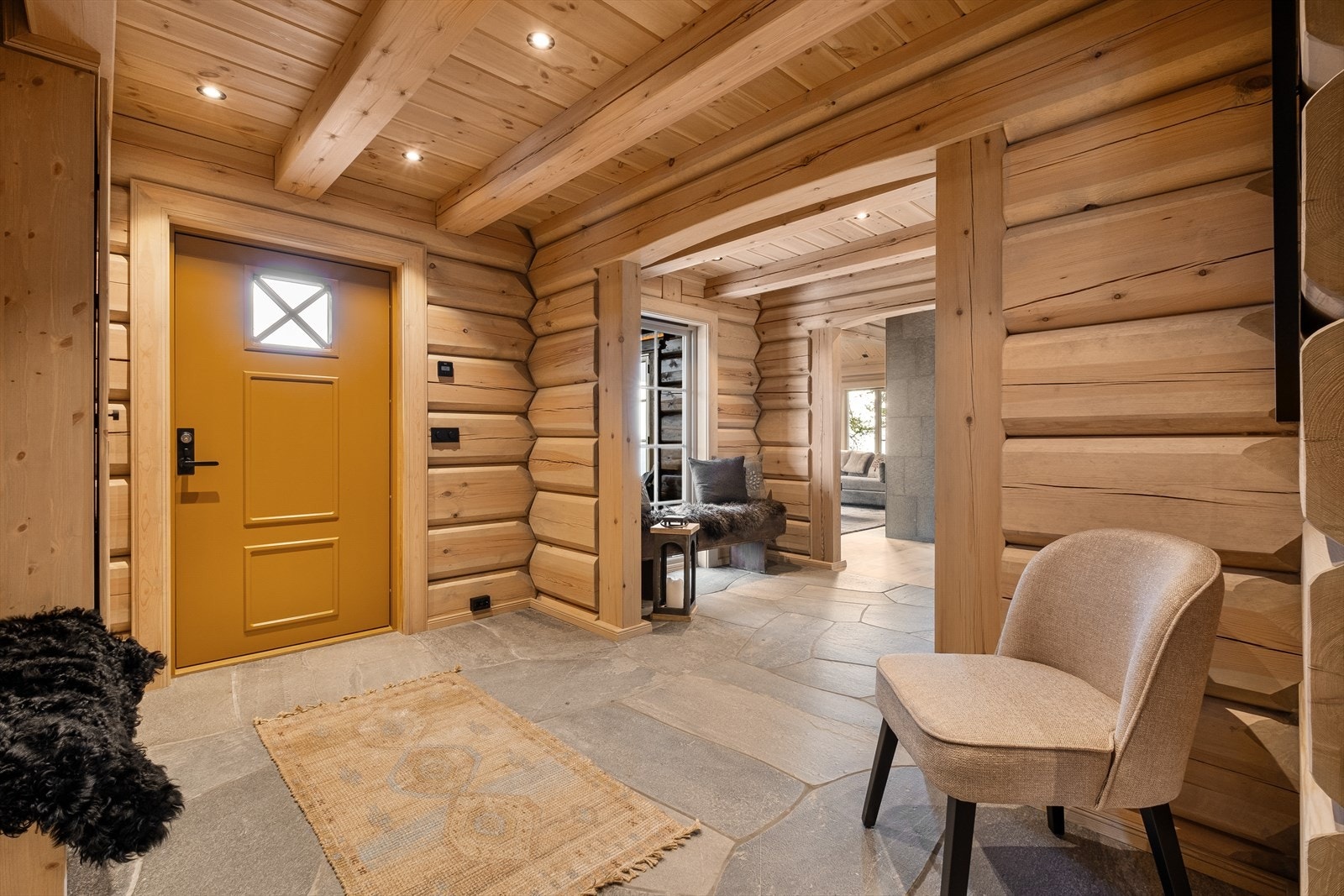 Inngangspartiet ønsker deg velkommen med skifer på gulvet og beiset trevegger som gir en rustikk sjarm, samtidig som det er lagt stor vekt på funksjonalitet med vannbåren gulvvarme gjennom hele hytten. Galleribilde