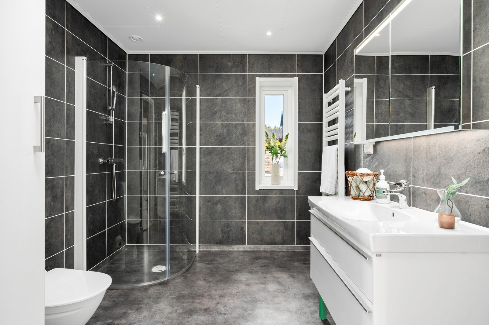 Baderommet har belegg på gulvet og våtromsplater på veggene. Det er elektrisk komfortvarme Galleribilde