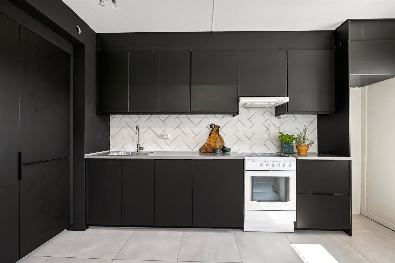 Kjøkkenet er godt utnyttet med både under- og overskap. Det er fiskebensfliser på vegg mellom benkeplaten og overskapene. Galleribilde