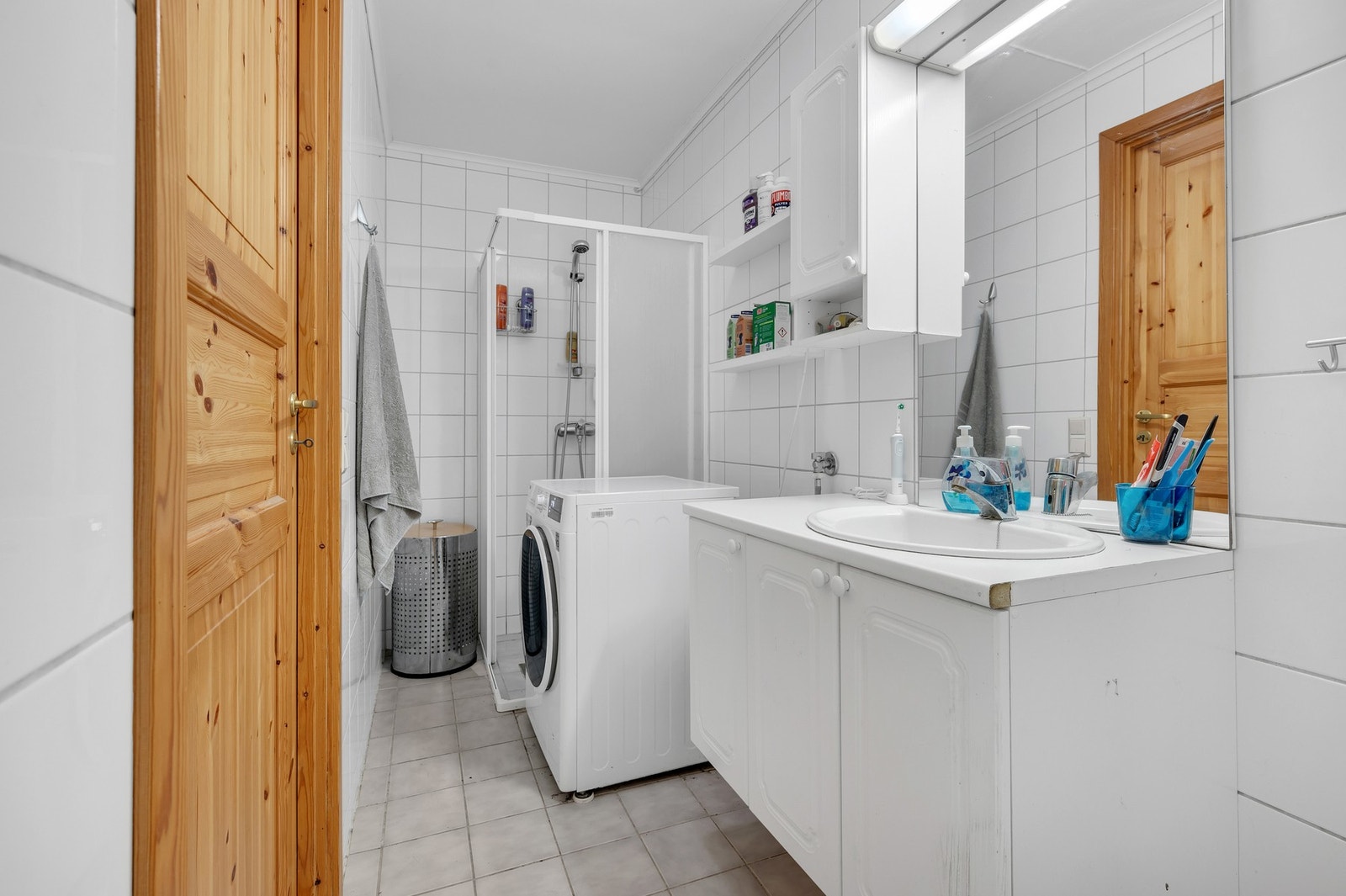 Praktisk bad i utleiedelen med hvite fliser, opplegg til vaskemaskin og god oppbevaringsplass. Galleribilde