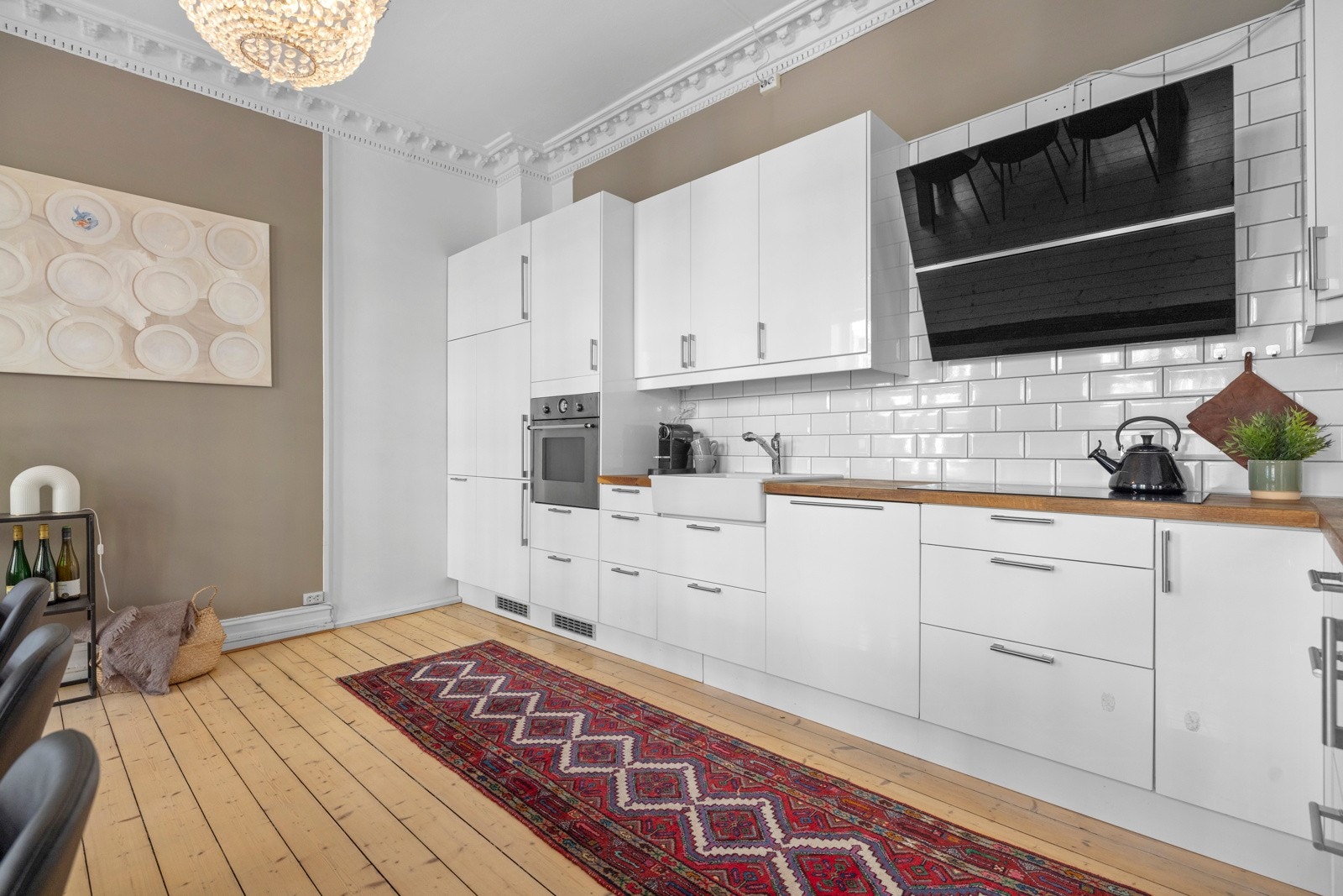 Kjøkkenet har glatte fronter med fliser på vegg over benk samt lys under overskap. Galleribilde