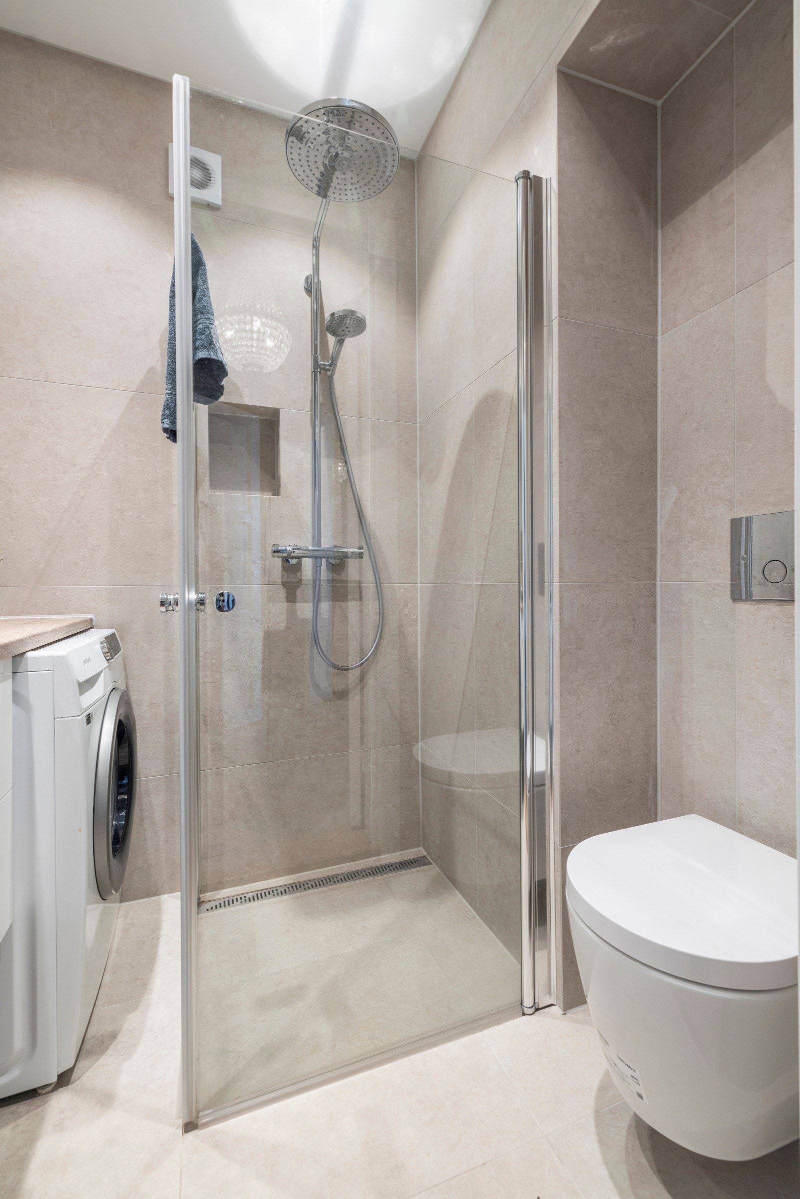Baderommet består av veggmontert toalett, nedsenket dusjsone med svingbare glassdører og regnfallsdusj, samt opplegg for vaskemaskin. Galleribilde