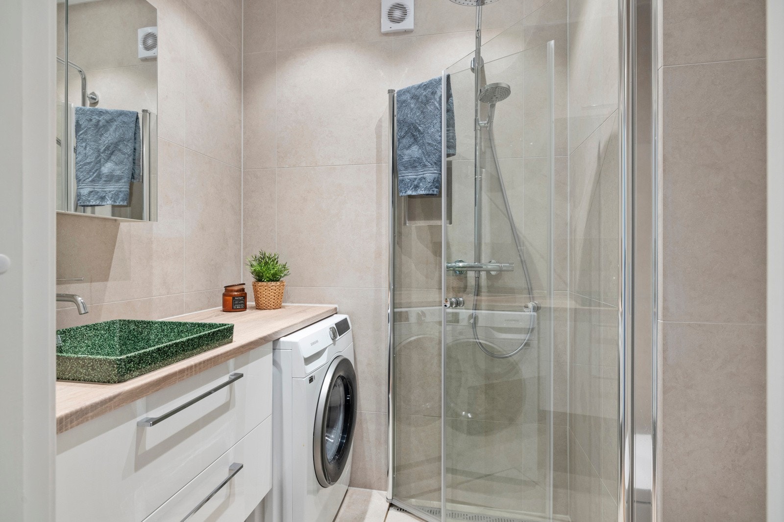 Pent baderom fra 2023 med store, delikate fliser i lys fargetone og varmekabler i gulvet. Galleribilde