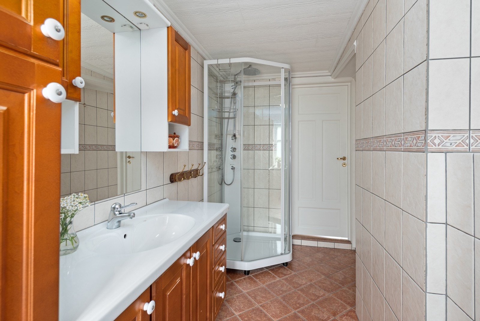 Badet i 1 etg har fliser på vegger og gulv, behagelig gulvvarme, dusjkabinett, og stor innredning med skapplass, samt vegghengt toalett. Galleribilde