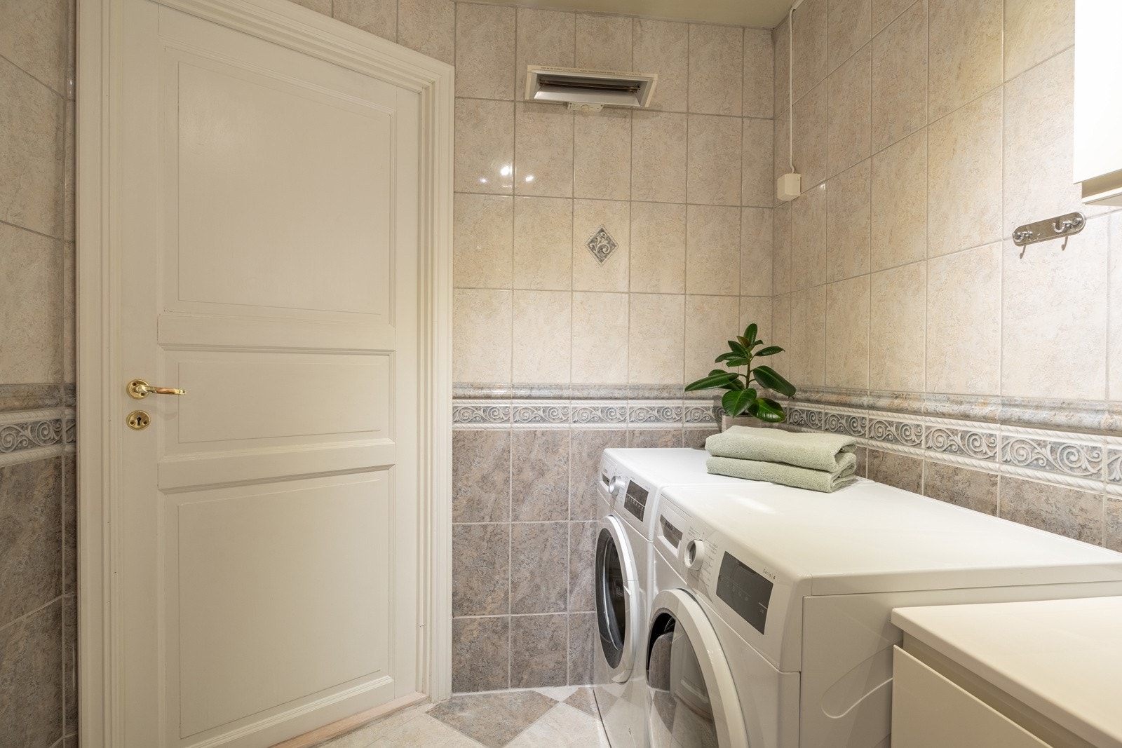 Badet har flislagte gulv og vegger og en elektrisk varmelampe på veggen. Galleribilde