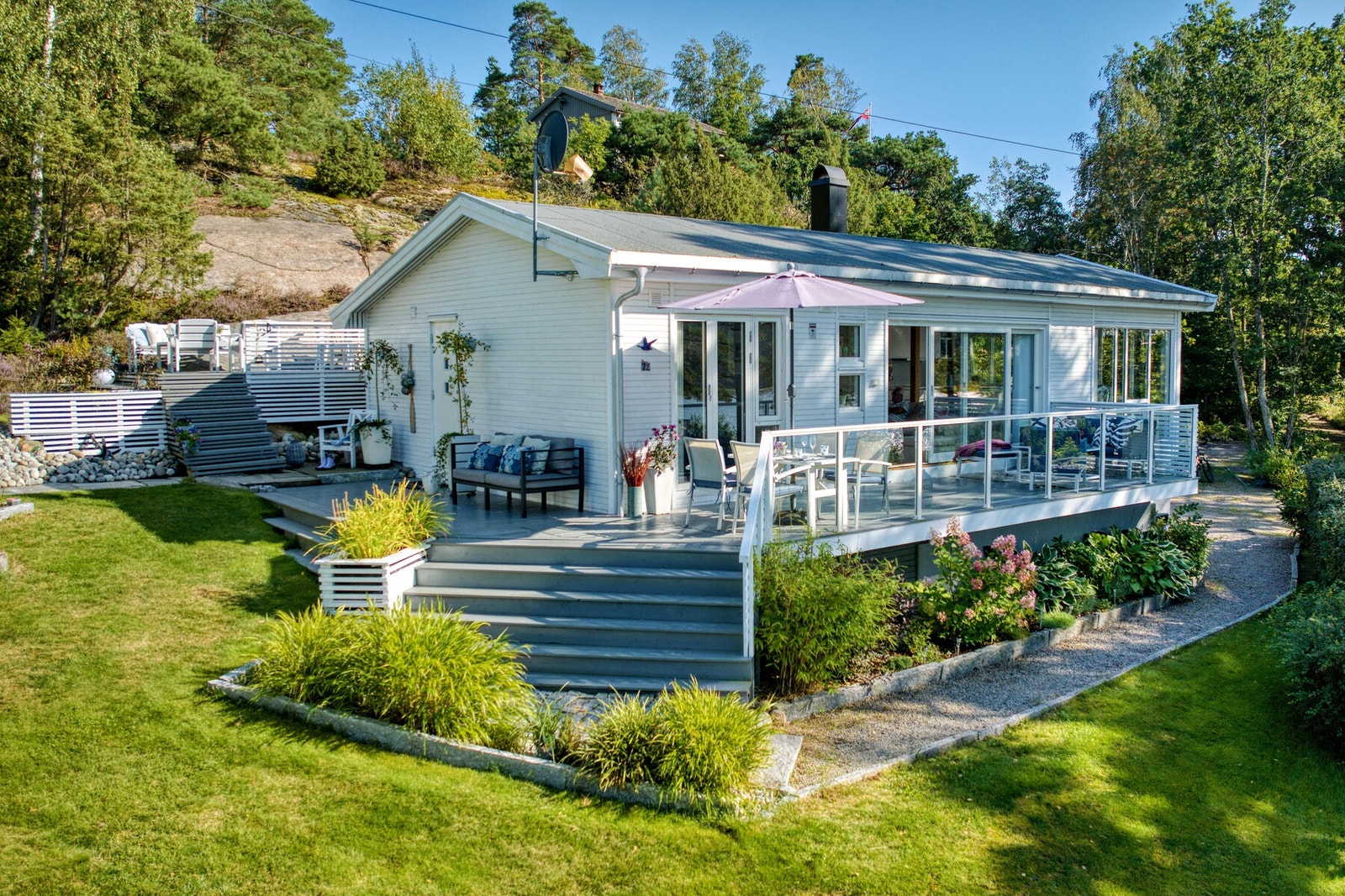 Dette er en elegant og sommerlig hytte tegnet av arkitekt Per Bjar - beliggende kun 75 meter fra sjøkanten og båtbrygge. Galleribilde