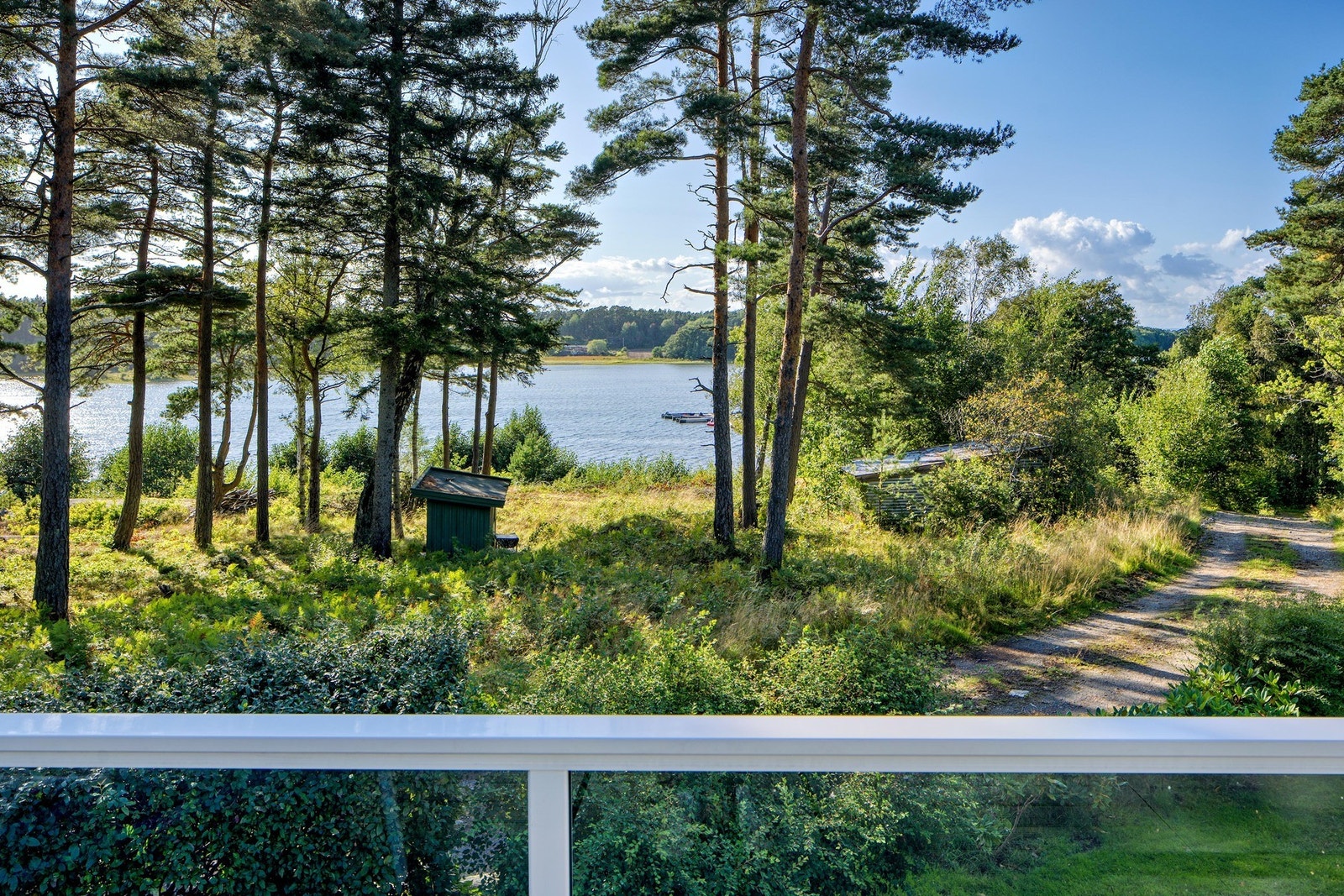 Under furukronene har du god kontakt med sjøen, fra verandaen og innenfra. Galleribilde