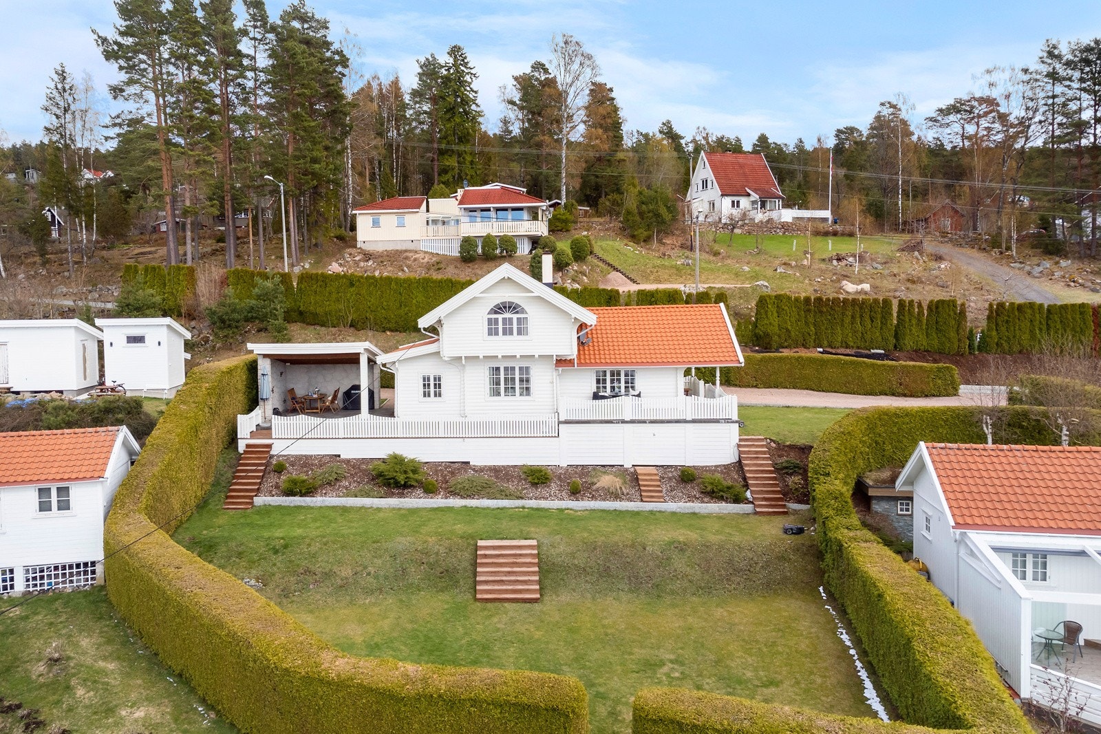 Tomten er pent opparbeidet med plener og beplantning samt formede grønne thujahekker som skjermer tomten mot innsyn | 2 el gressklippere tar seg av plenene Galleribilde