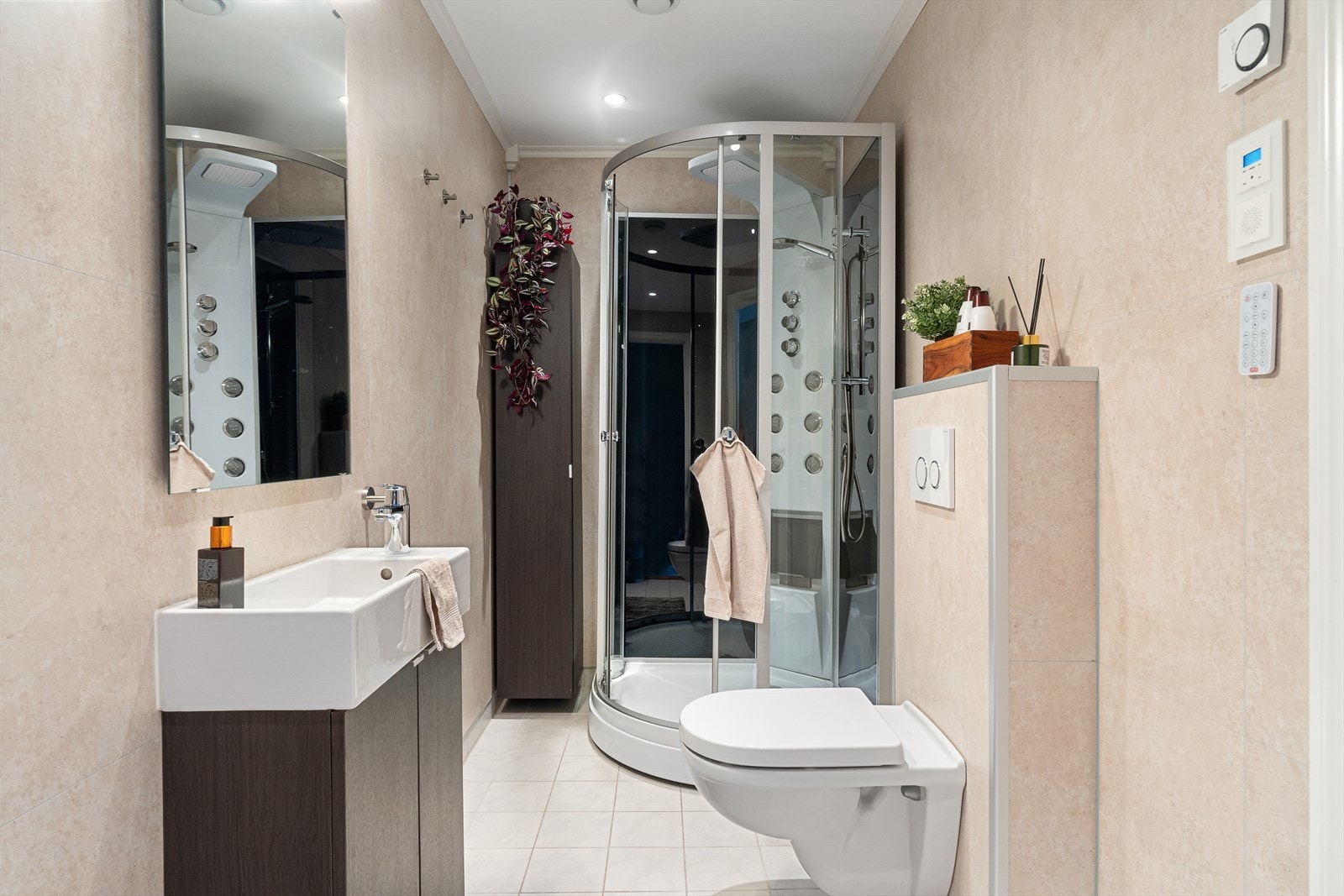 Bad er praktisk innredet med dusjkabinett, vegghengt toalett, servantskap med speil og høyskap. Galleribilde