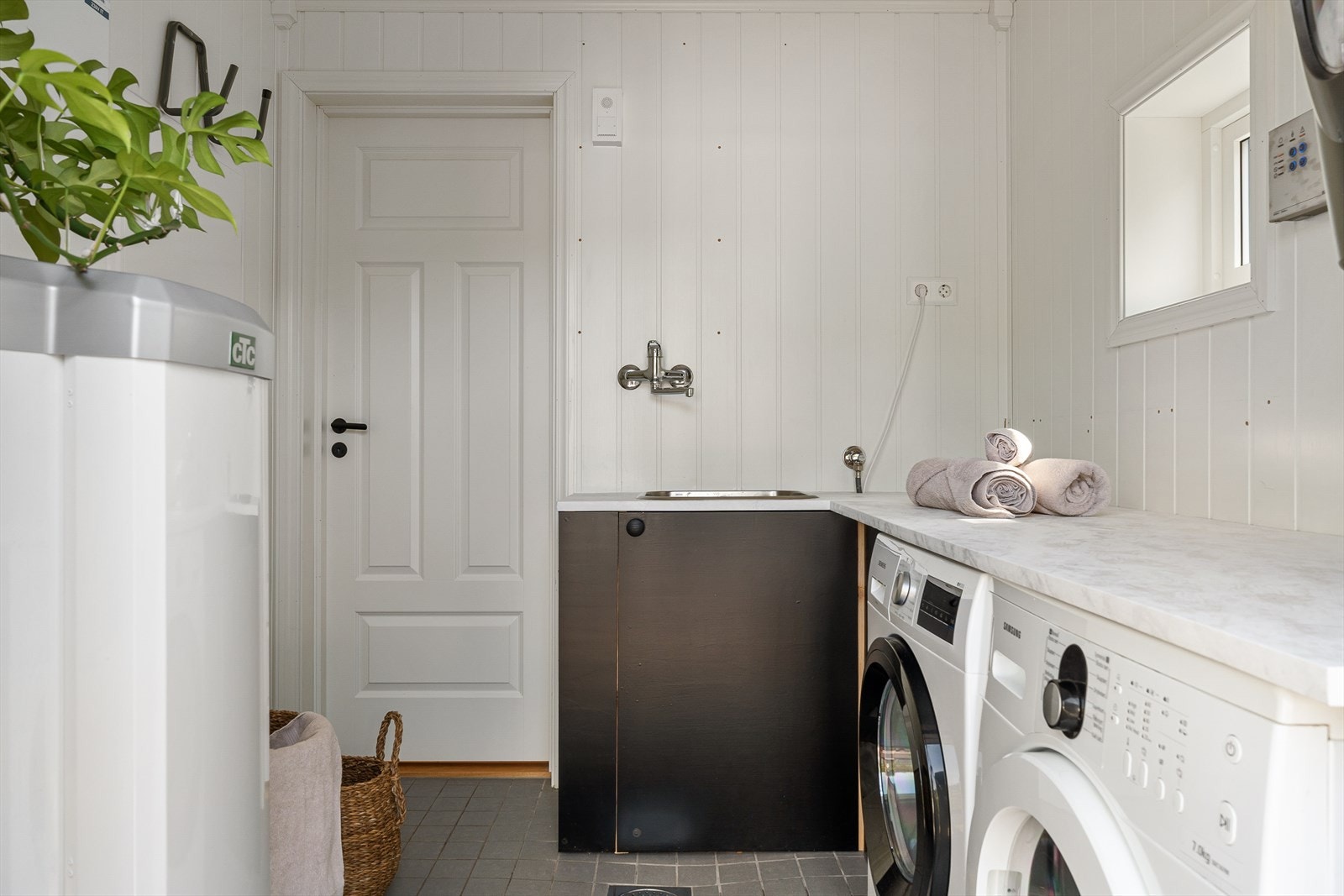 Vaskerommet er praktisk innredet med vask og benkeplate tilrettelagt for å passe over vaskemaskin og tørketrommel. Galleribilde