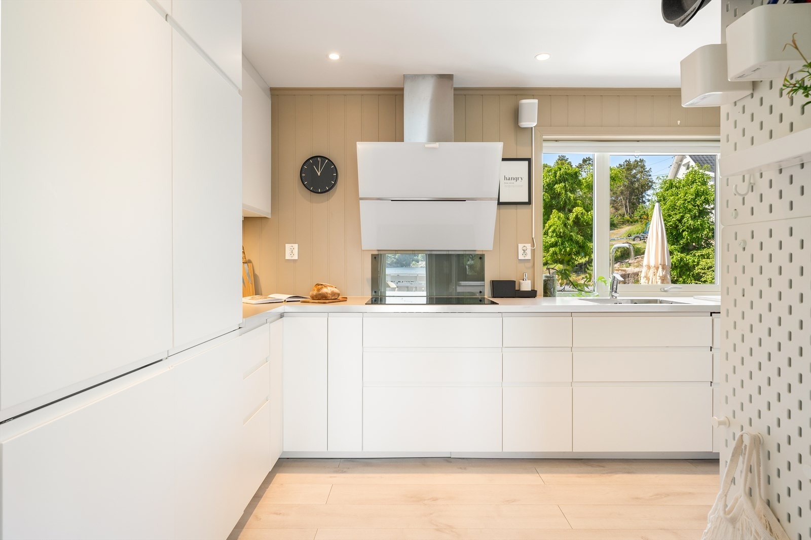 Kjøkkenet er praktisk innredet med en tidløs innredning med hvite, slette fronter og laminat benkeplate. Galleribilde