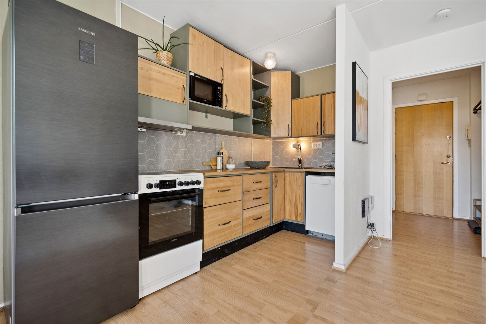 Innredningen består av heltre benkeplate med nedfelt sort kum, ettgreps kjøkkenkran, frittstående komfyr, frittstående kjøl/frys og oppvaskmaskin. Galleribilde