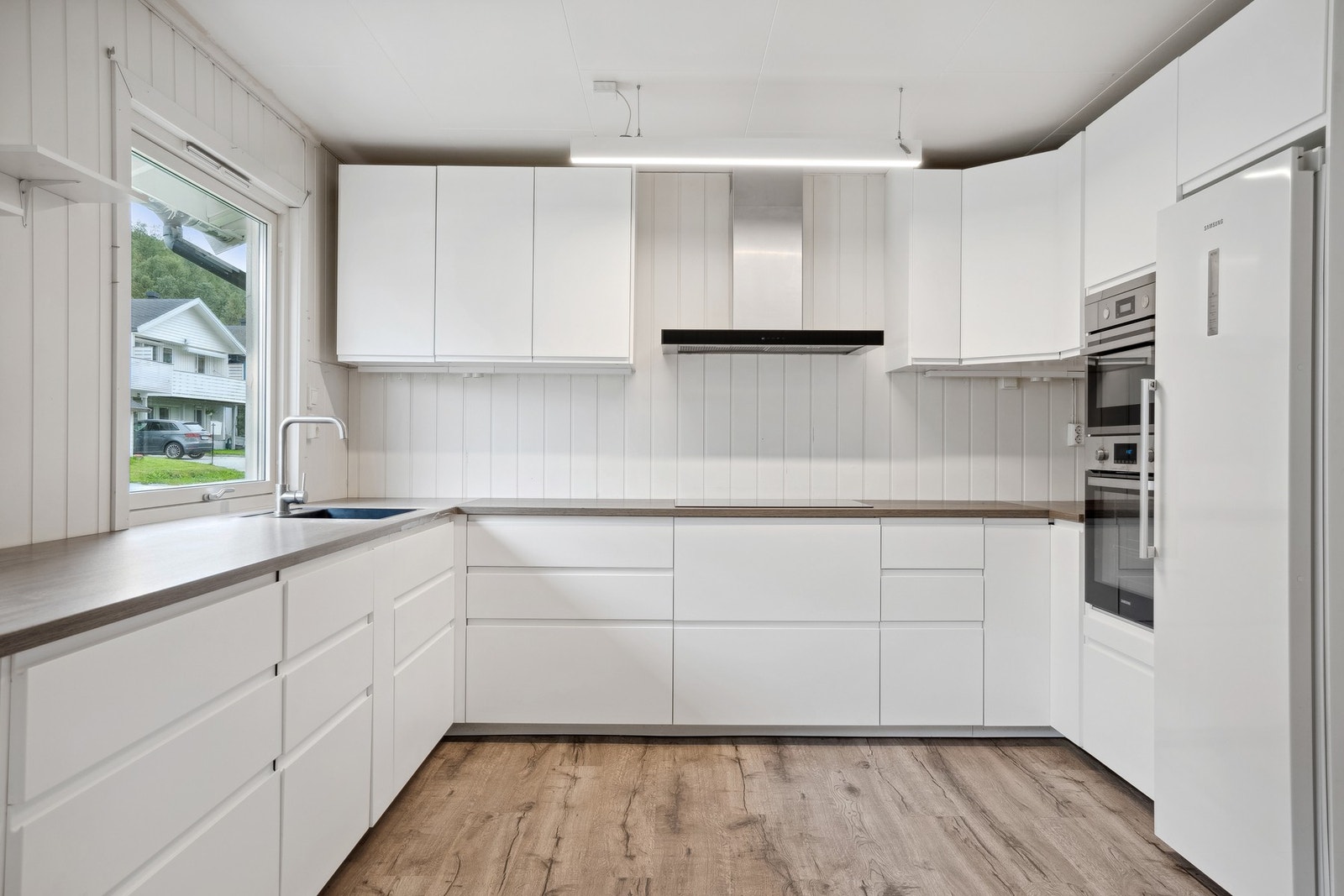 Et stort og moderne kjøkken med integrerte hvitevarer Galleribilde