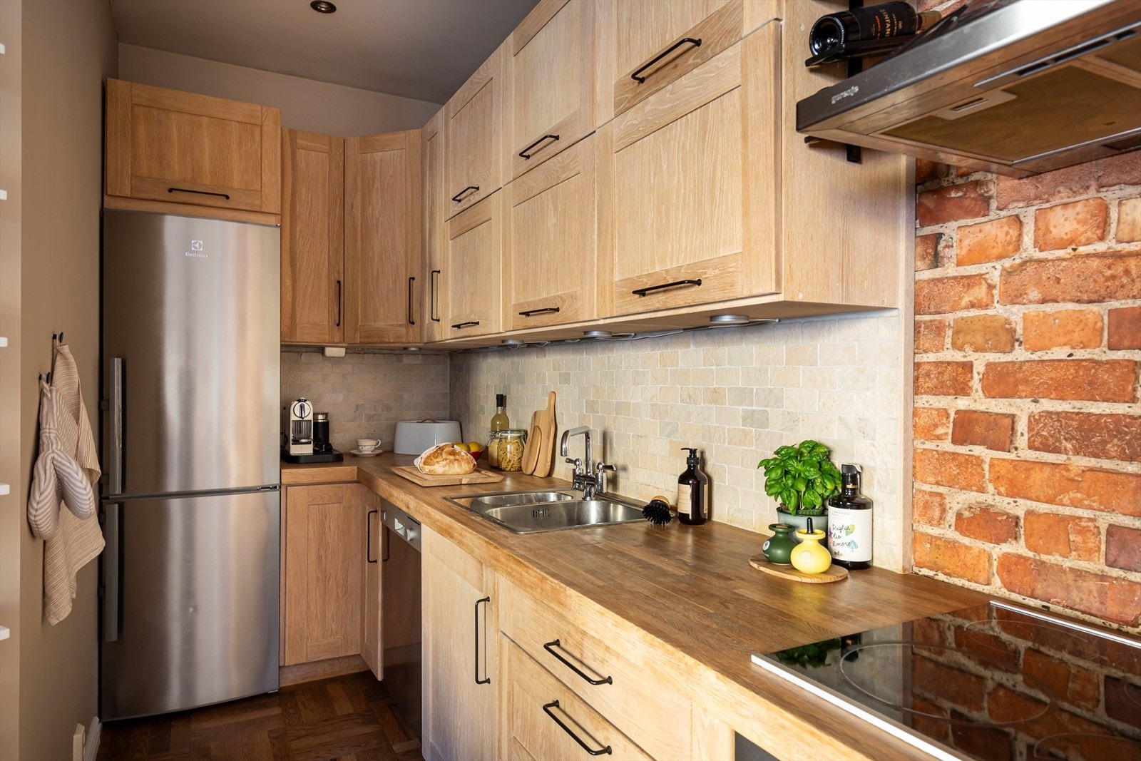 Videre består kjøkkeninnredningen av nedfelt kum i rustfritt stål og integrerte hvitevarer som platetopp, oppvaskmaskin og stekeovn. Galleribilde