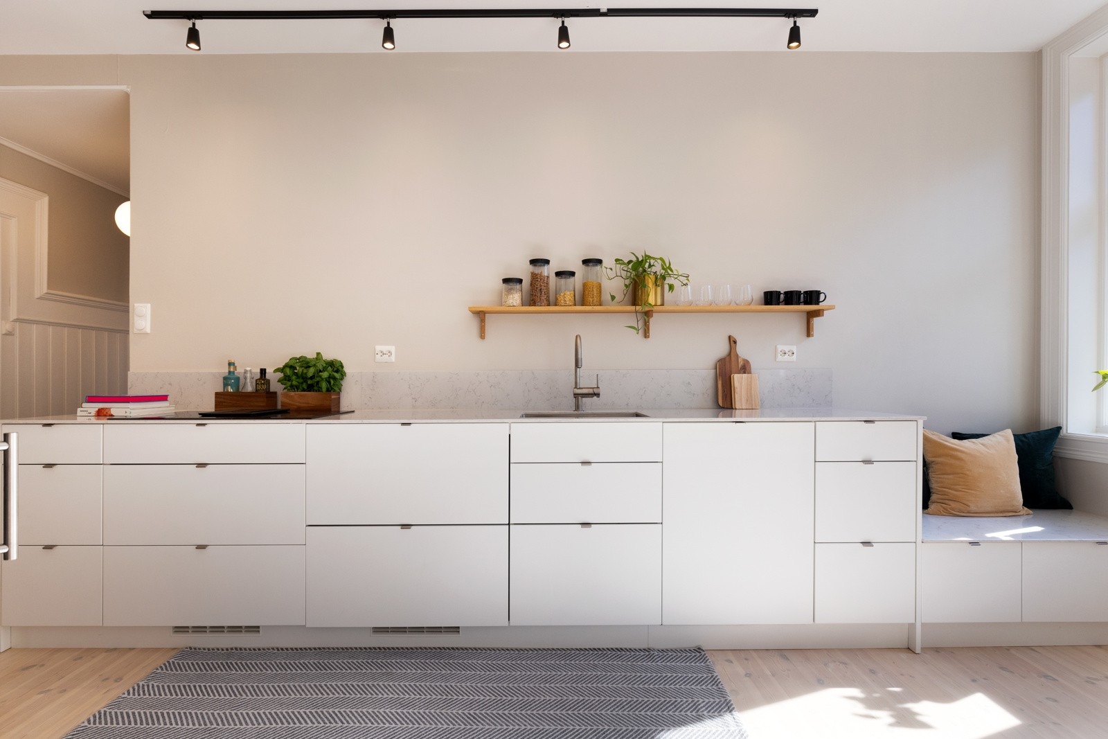 Hvite, glatte fronter og steinbelagte flate over benkeplate av kompositt gir et stilrent uttrykk. Galleribilde