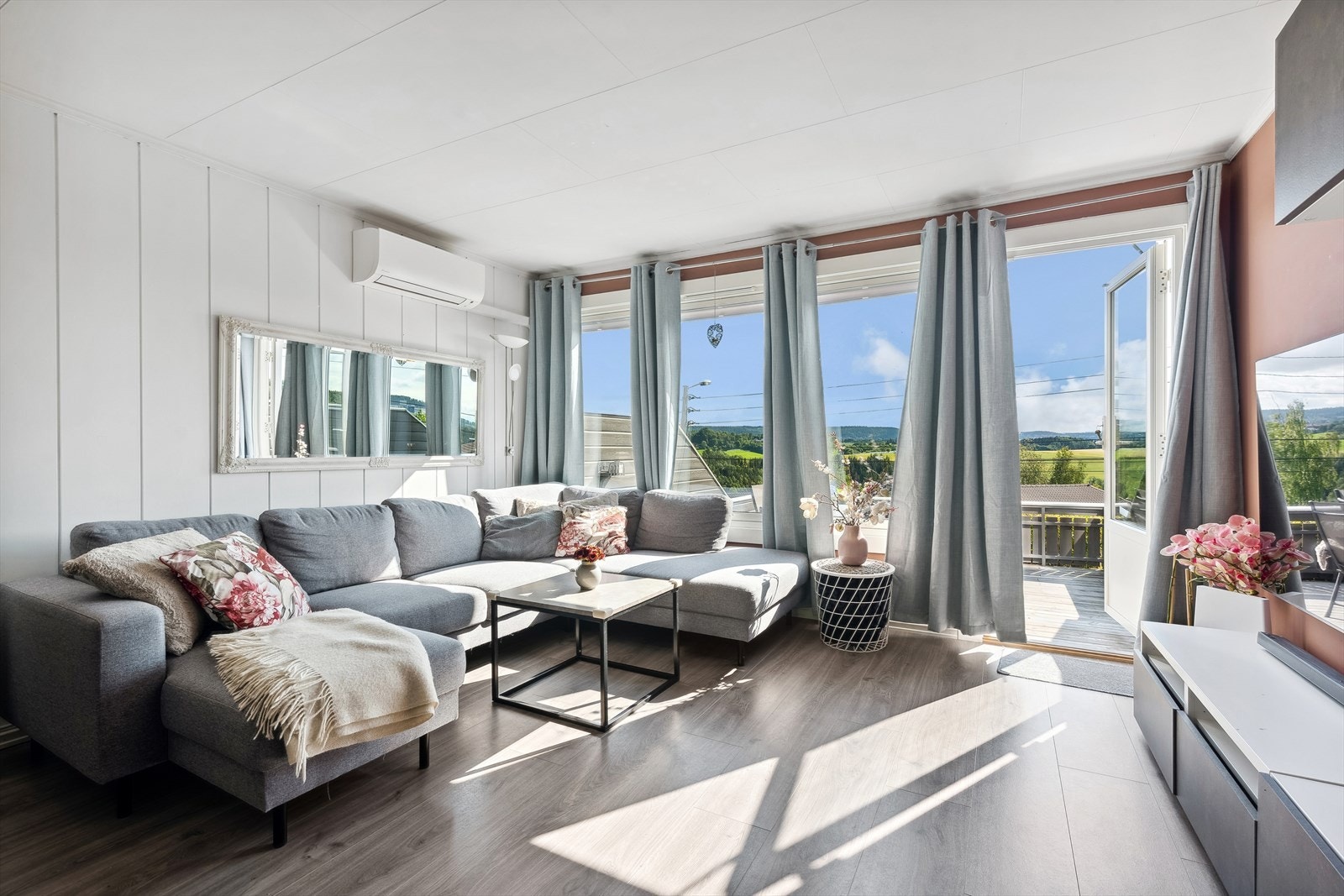 Stuen er lys og trivelig med store vinduer som gjør at dagslyset flommer inn Galleribilde