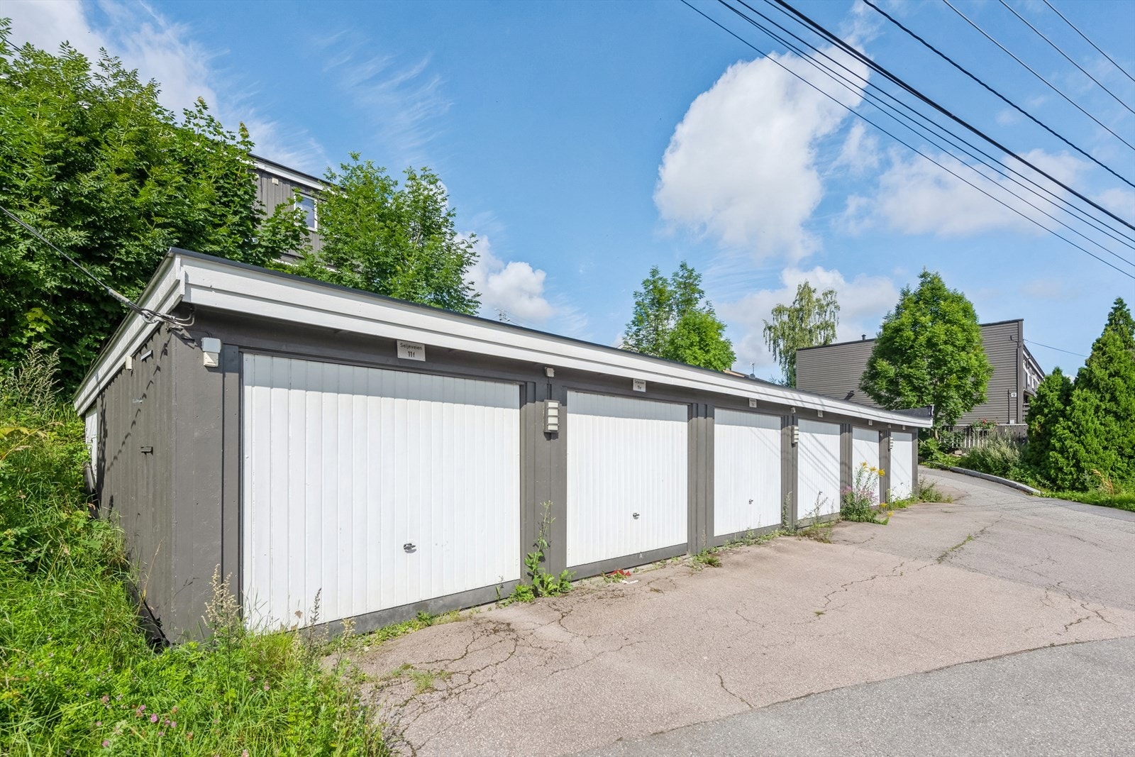 Med rekkehuset følger garasjeplass. Elbil-lader var ny i 2023. Ellers gjesteparkering på parkeringsplass ovenfor boligrekka Galleribilde