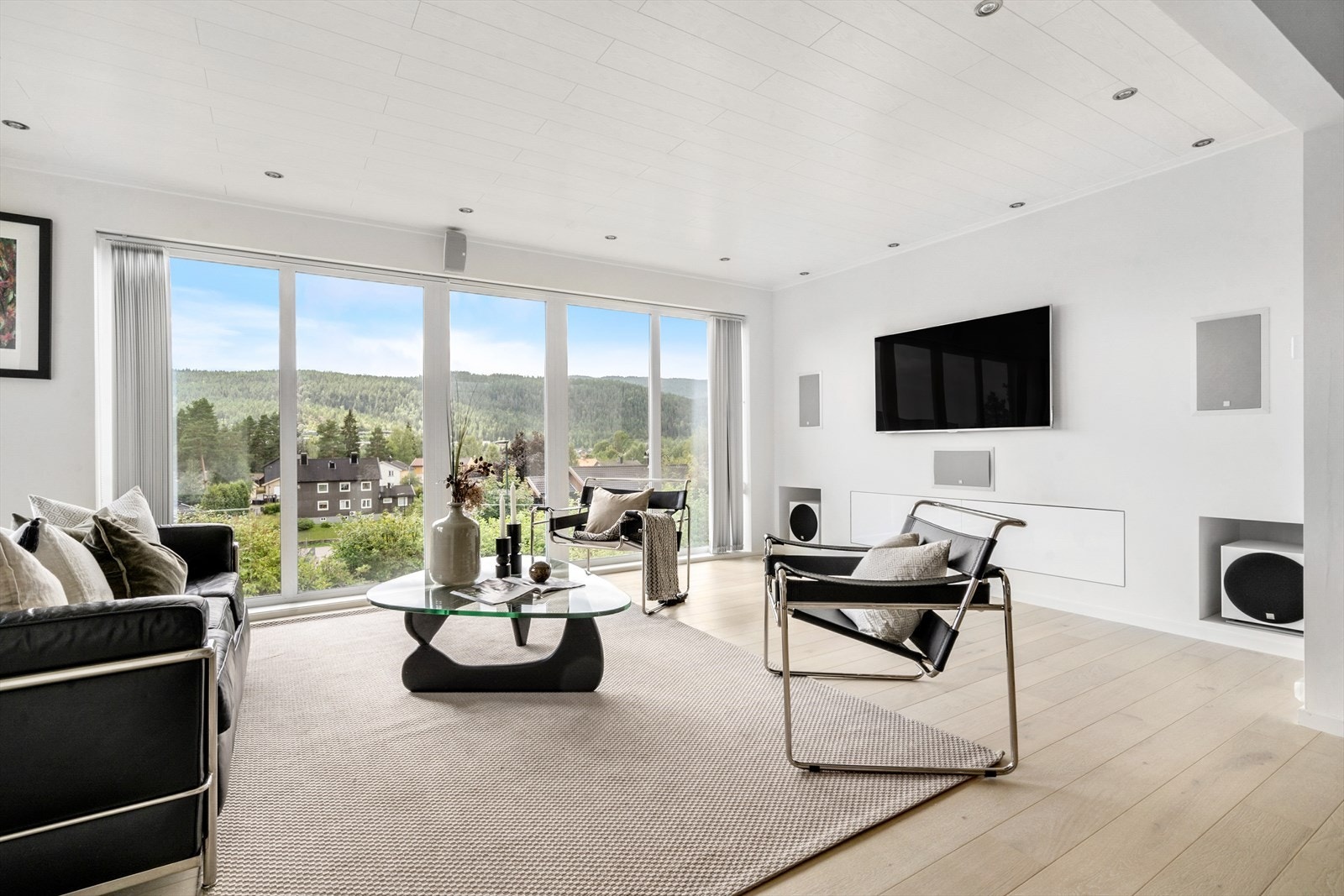 Adskilt tv-stue med ny parkett fra 2024 i "white oak" utførelse, i tv-stuen er det rom for en romslig sofakrok og tv-møblement i tillegg har rommet integrerte høyttalere i veggen. Galleribilde