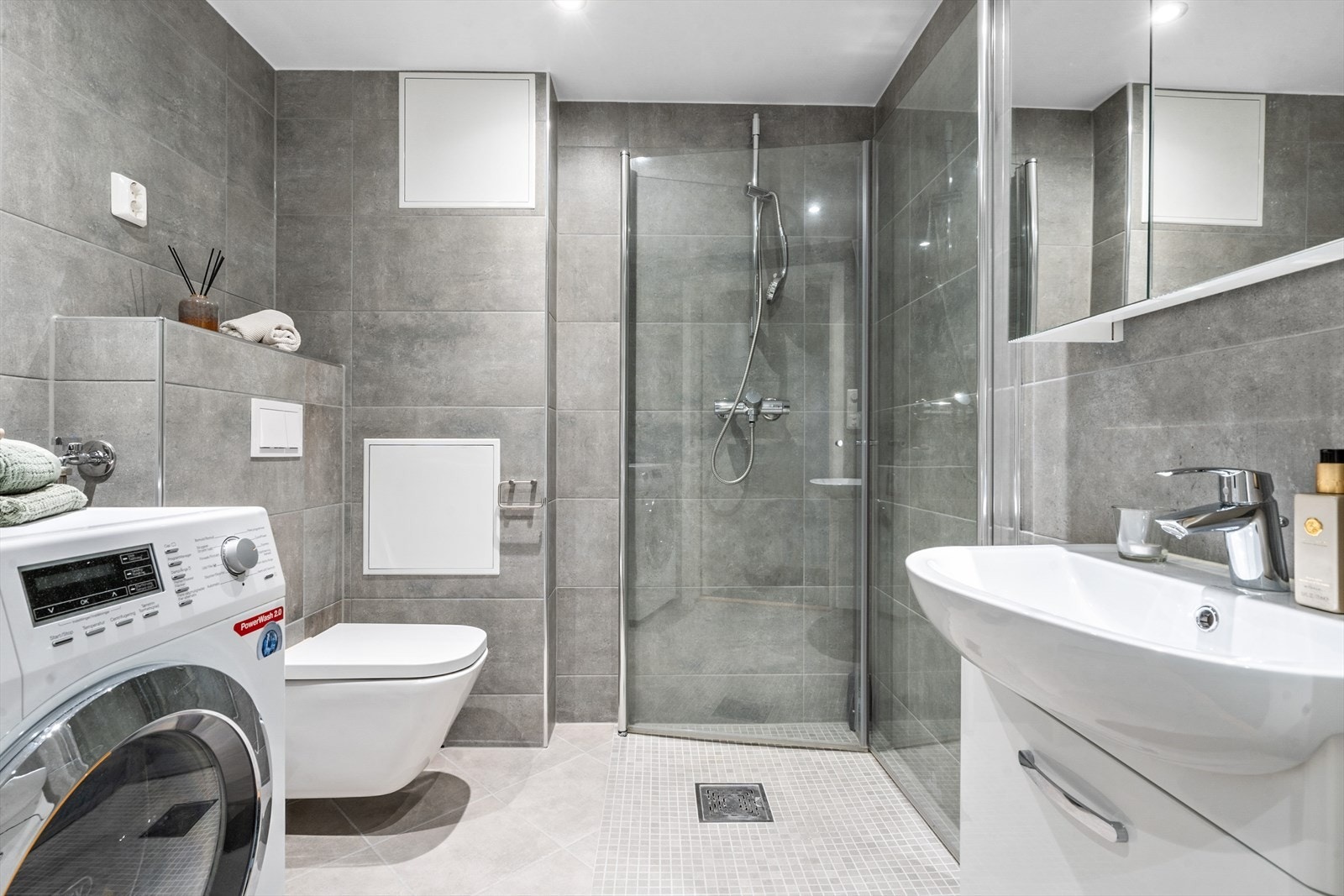 Høyst moderne flislagt bad i underetasjen med mosaikkfliser i dusjsonen og downlights i tak, rommet har varmekabler i gulv. Galleribilde