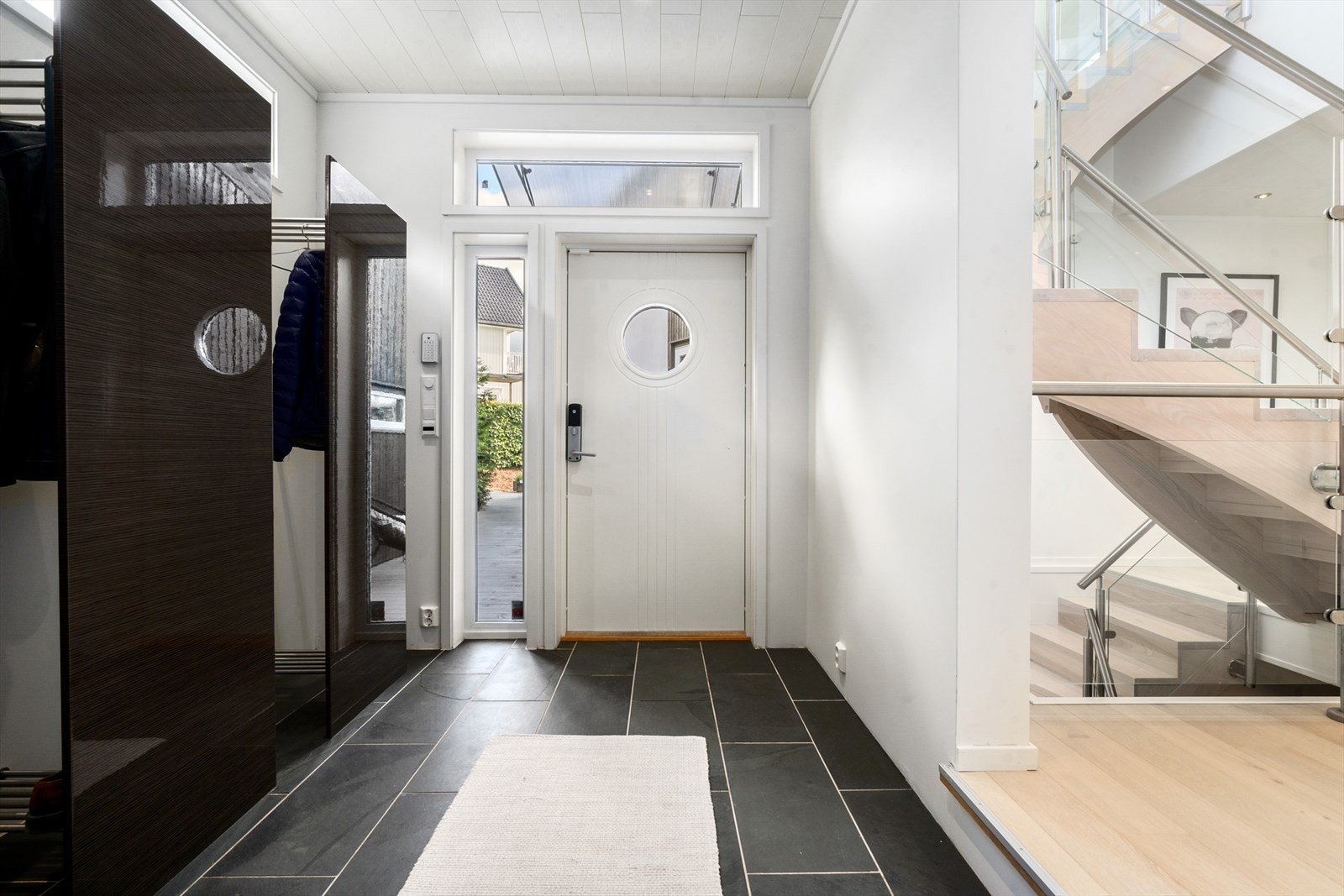 Lys og romslig, flislagt entré med god plass til å henge ifra seg yttertøyet i garderobeskap. Inngangsdøren har en praktisk kodelås fra Yale doorman. Galleribilde