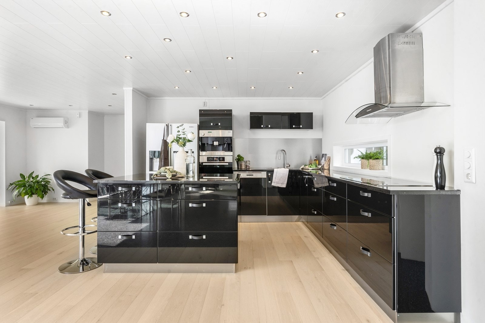 Delikat kjøkkeninnredning fra kvalitetsprodusenten Kvikk med glatte, sorte høyglansede fronter og benkeplate av steinen, larvikitt som bærer et harmonisk samspill mellom eleganse og funksjonalitet. Galleribilde