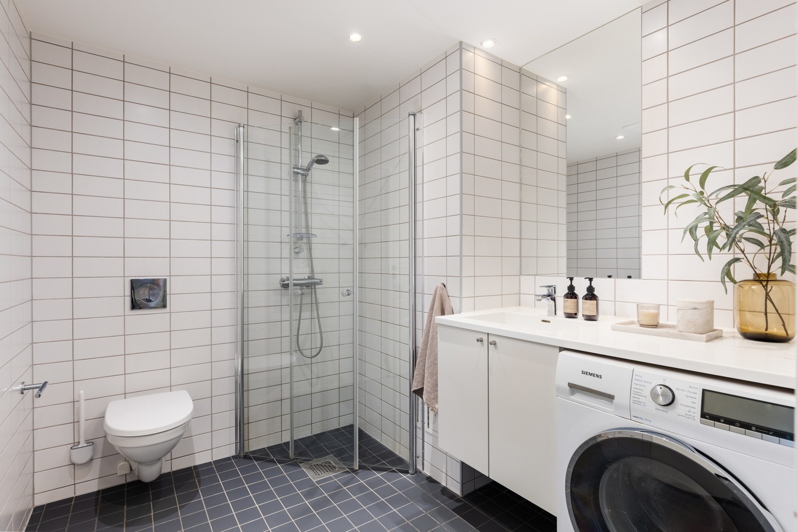Badet har vegghengt toalett, dusjløsning og opplegg for vaskemaskin. Galleribilde