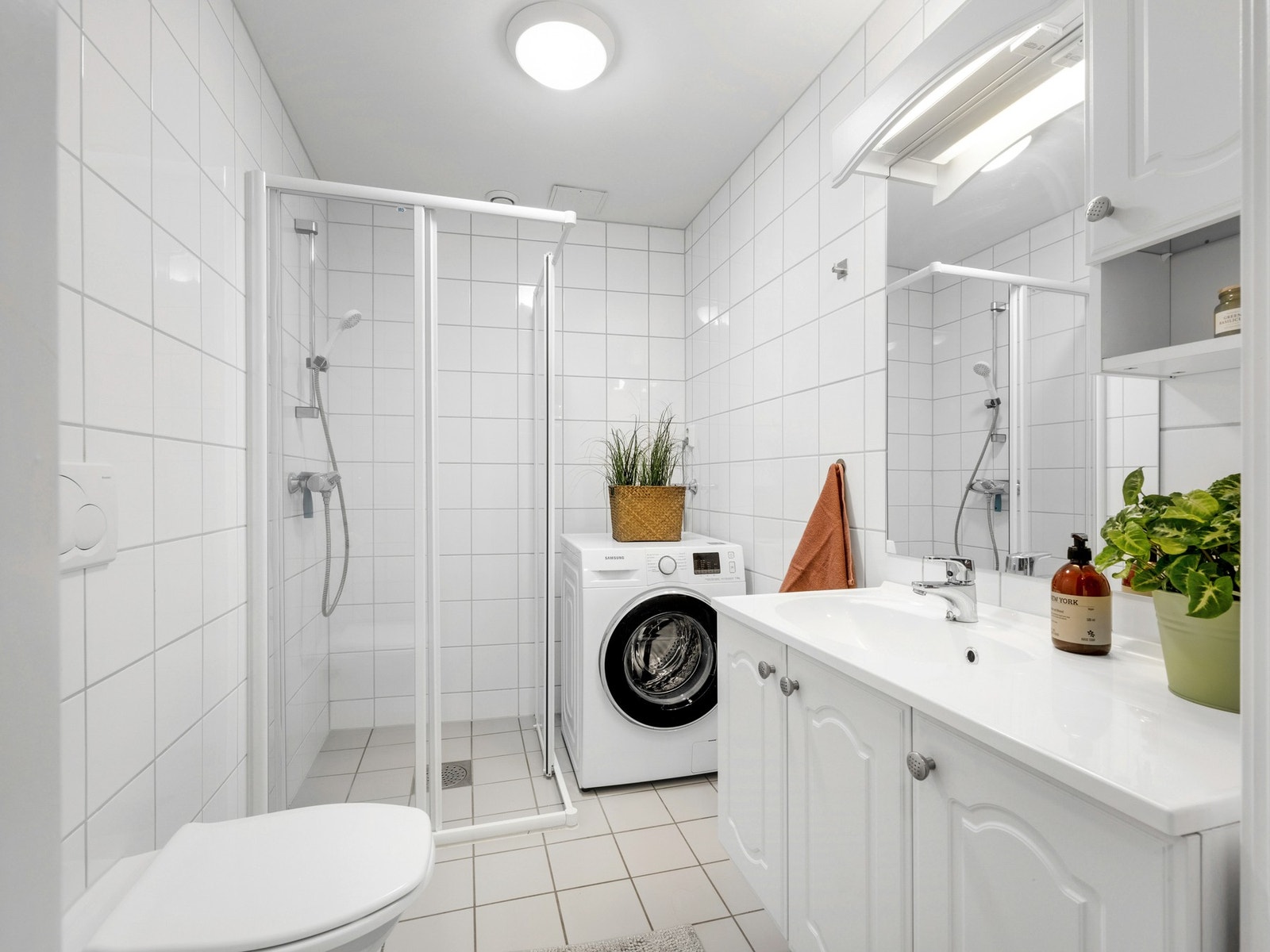 Romslig bad med flislagte flater og varmekabler i gulv. Stor dusjnisje og opplegg for vaskemaskin. Galleribilde