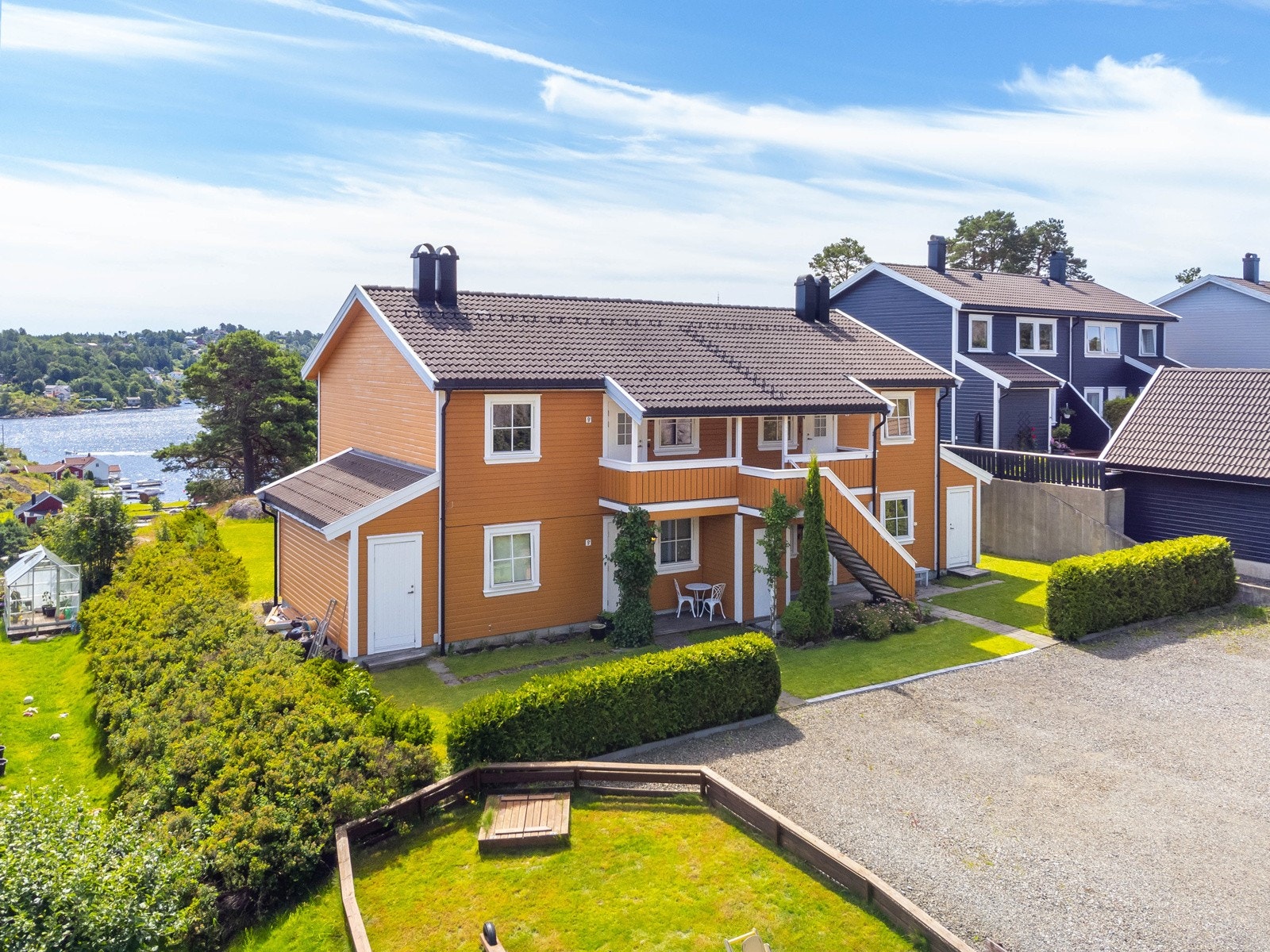 Pent opparbeidet uteområde med gruset innkjørsel, og felles trappeoppgang. Leiligheten ligger øverst til venstre. Galleribilde