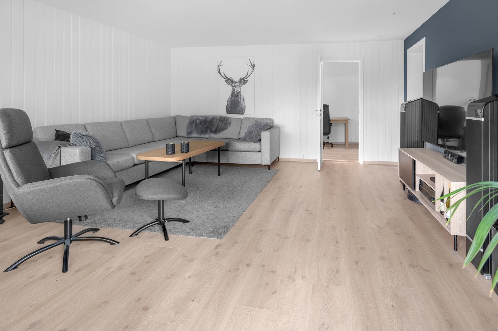 Også i stuen er det lagt 1-stavs laminat med malt panel på to vegger og spotdownlights i tak. Galleribilde