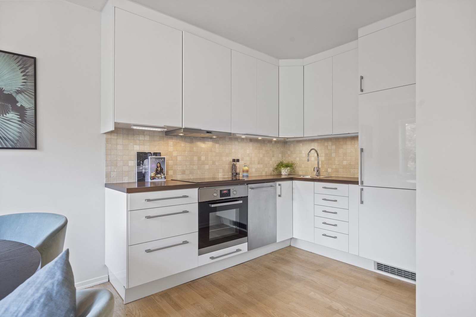 Stilrent kjøkken med benkeplate av laminat og fliser mellom kjøkkenbenk og overskap Galleribilde