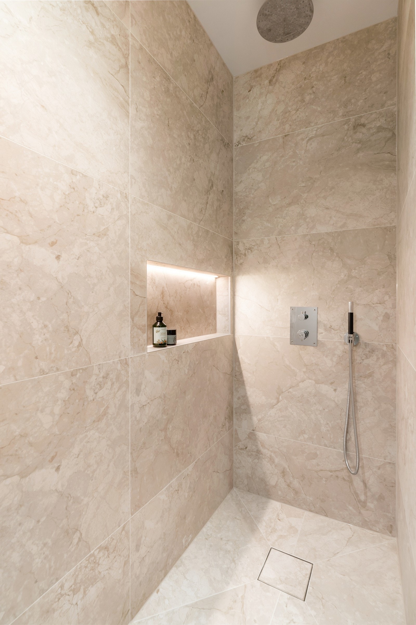 Dusjhjørnet er flislagt i lyse fliser med innfellt hylle. Galleribilde