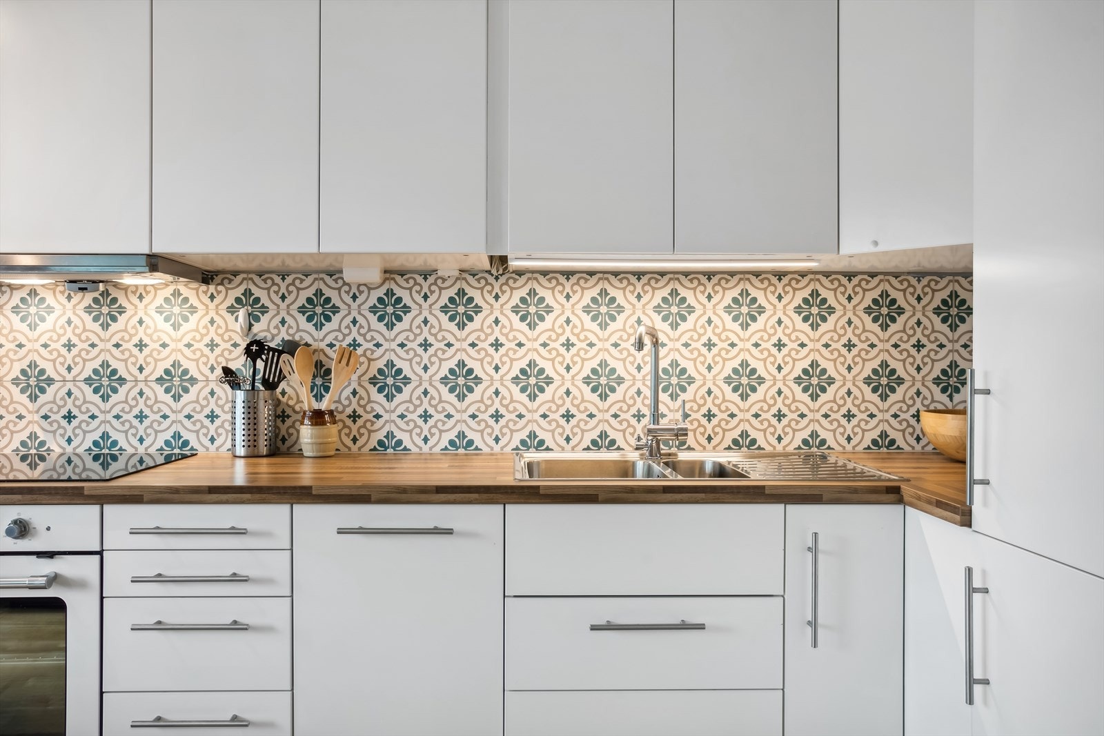 IKEA kjøkkeninnredning med hvite matte fronter og med takhøye skap, benkeplater i laminat, rustfri oppvaskkum med avrenningsplate, ventilator med kullfilter og integrerte hvitevarer. Galleribilde