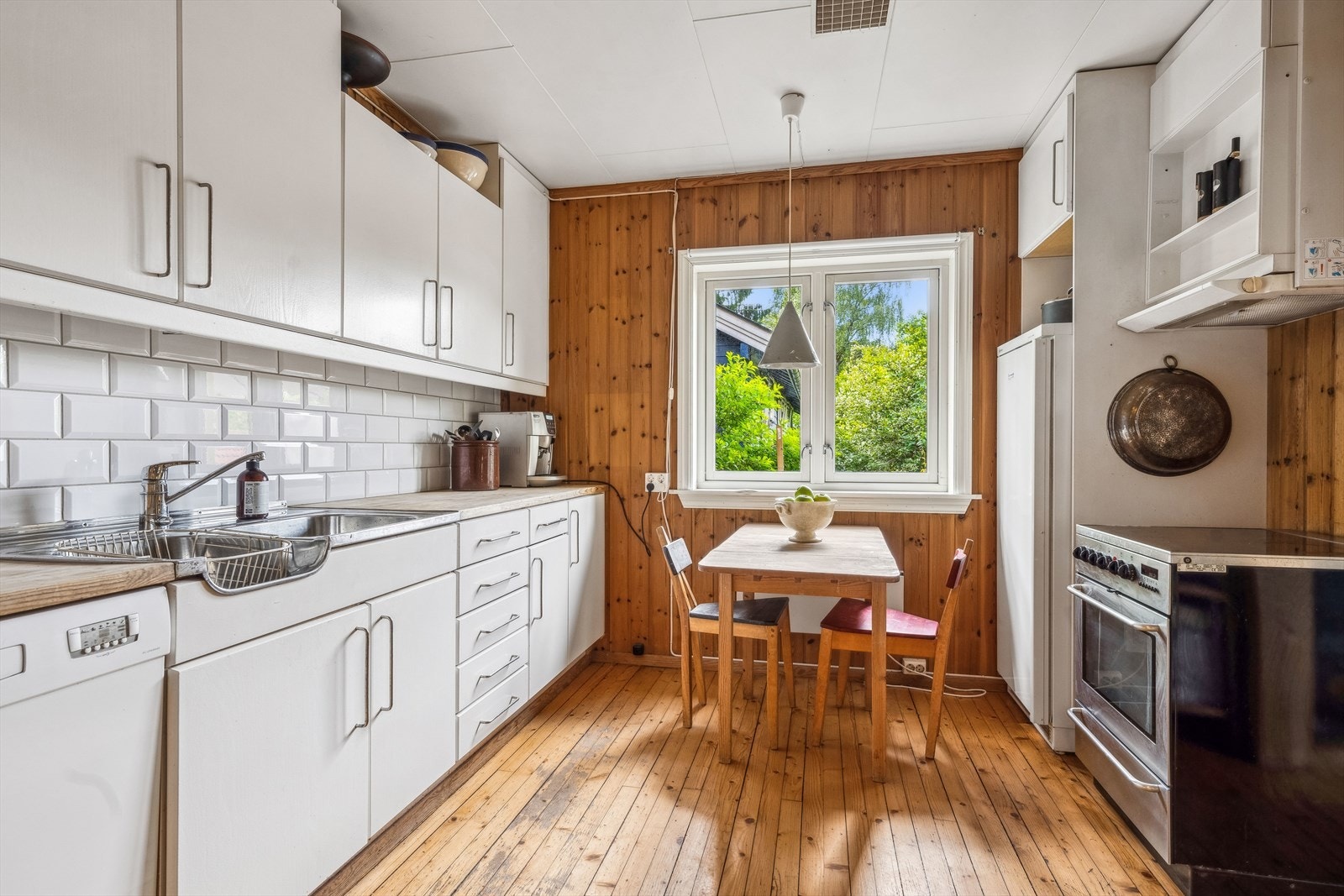 Koselig kjøkken med flis på vegger over benkeskap og glatte fronter. Galleribilde