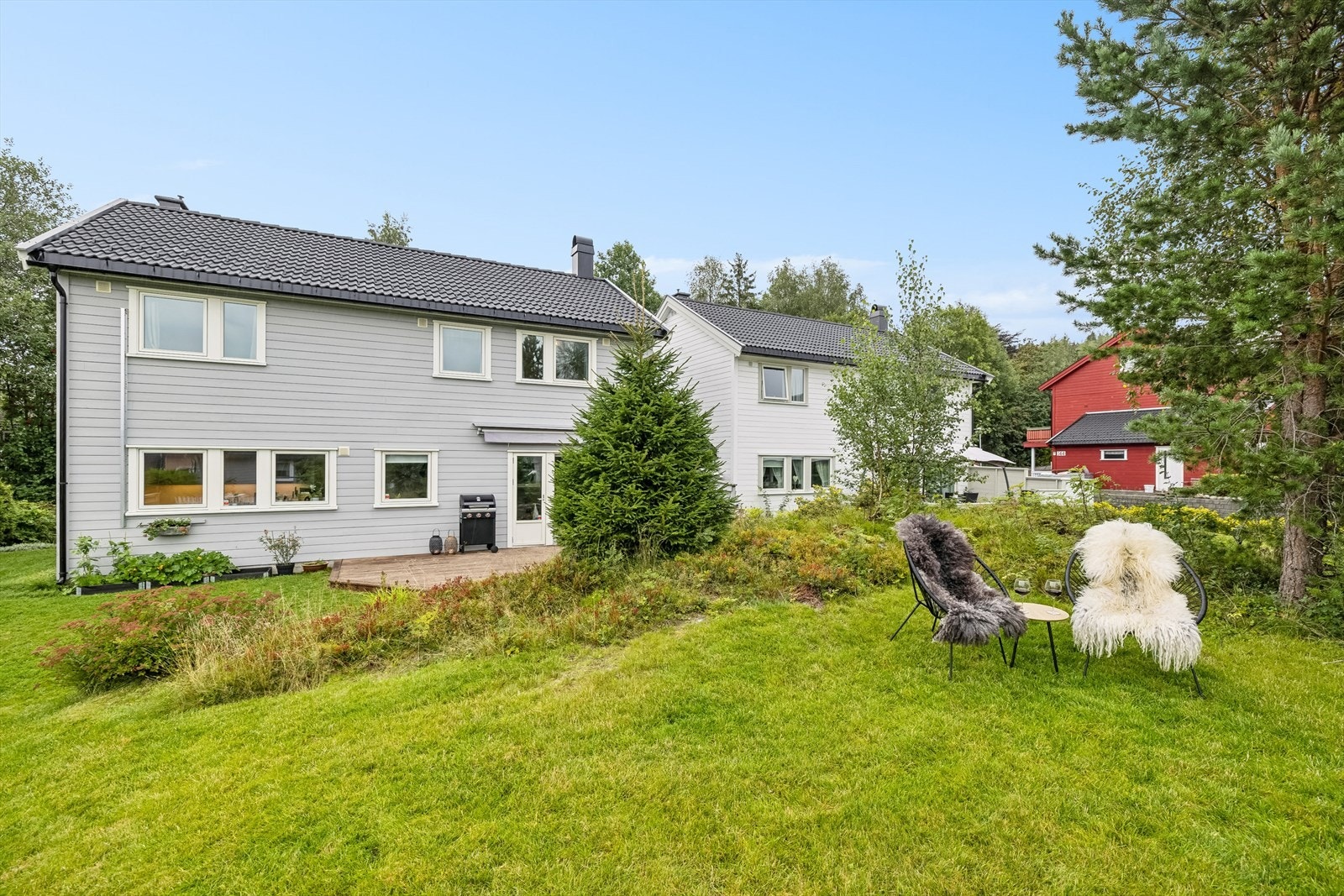 Fine utearealer som er opparbeidet med gressplen, trær, beplantninger og terrasseplatting. Galleribilde