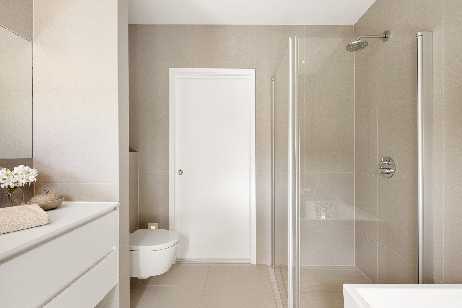 Badet har vegghengt toalett og et dusjhjørne med regnfallsdusj og innfellbare glassdører Galleribilde