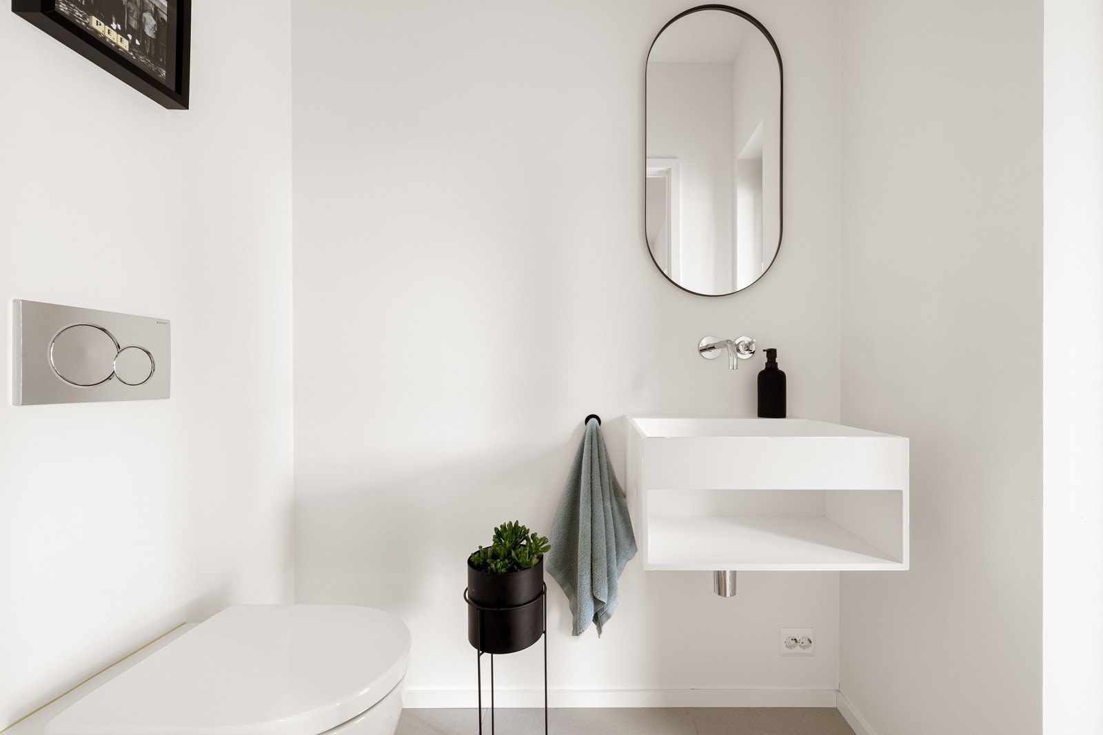 Wc-rommet er holdt i stilrent hvitt mot grå gulvfliser, og i tillegg til et vegghengt toalett har rommet en moderne servantinnredning Galleribilde