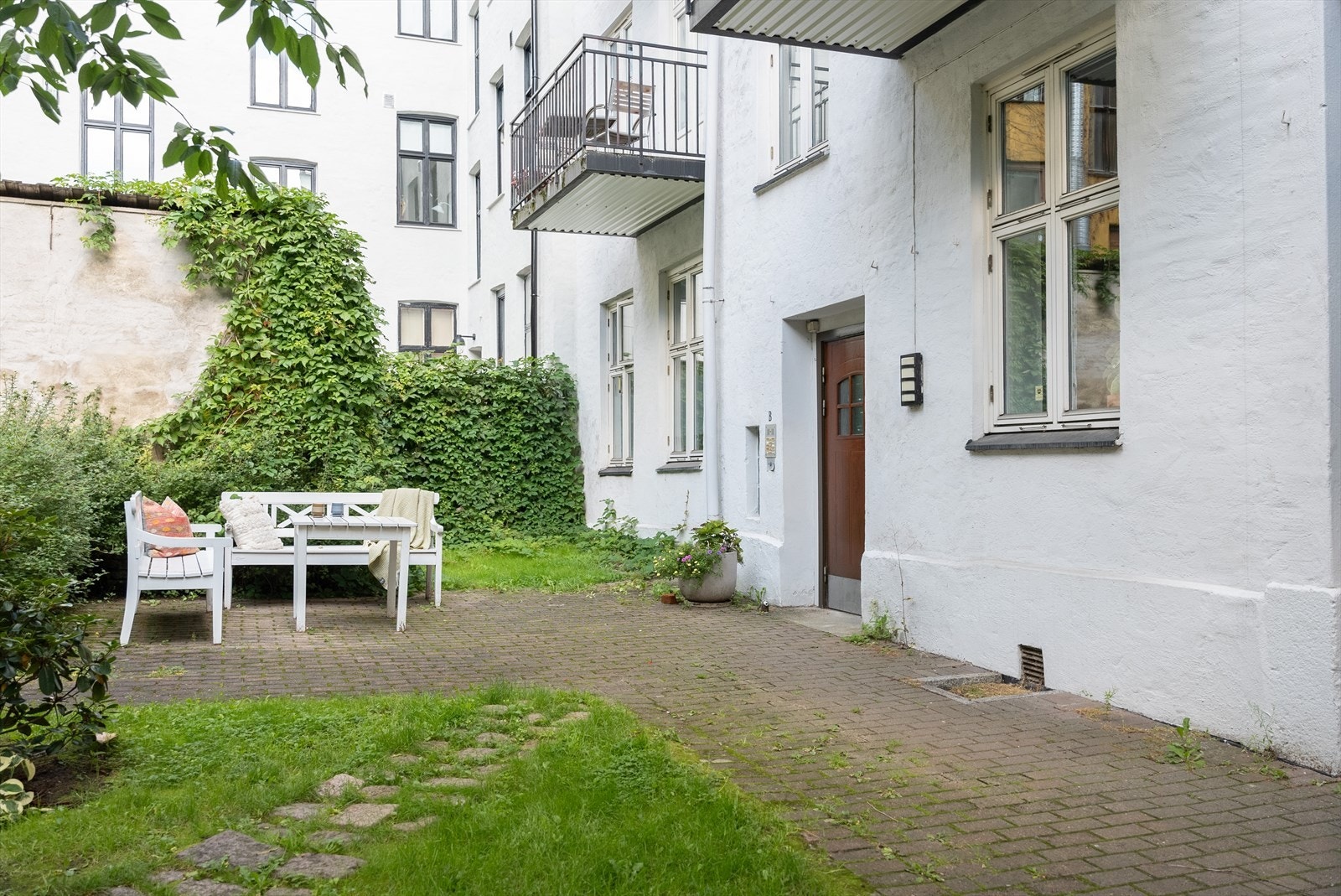 Bakgården er idyllisk. Med benker og bord kan du sitte ute i fred og ro midt i byen. Bare fire trappetrinn fra leiligheten Galleribilde