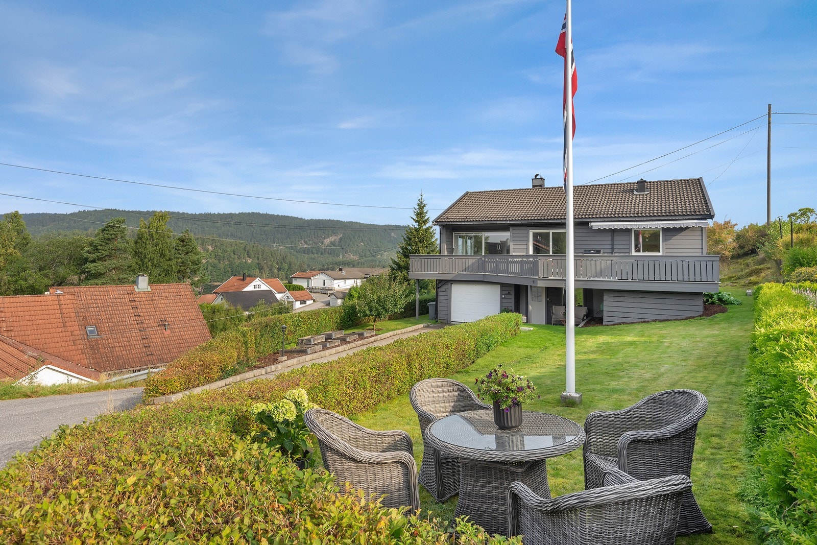 Pent opparbeidet tomt med plen, flaggstang, blomsterbed, hekk, diverse beplantning, m.m. Galleribilde