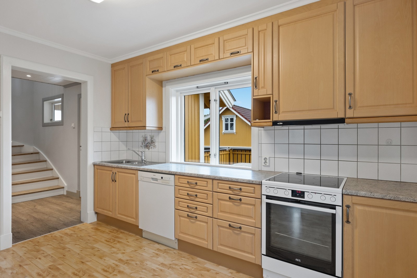 Kjøkkenet har praktisk inngang både i fra mellomgangen og i fra stua. Det er innredning fra 1995, med profilerte fronter og laminert benkeplate. Frittstående hvitevarer, med ventilator over komfyren Galleribilde