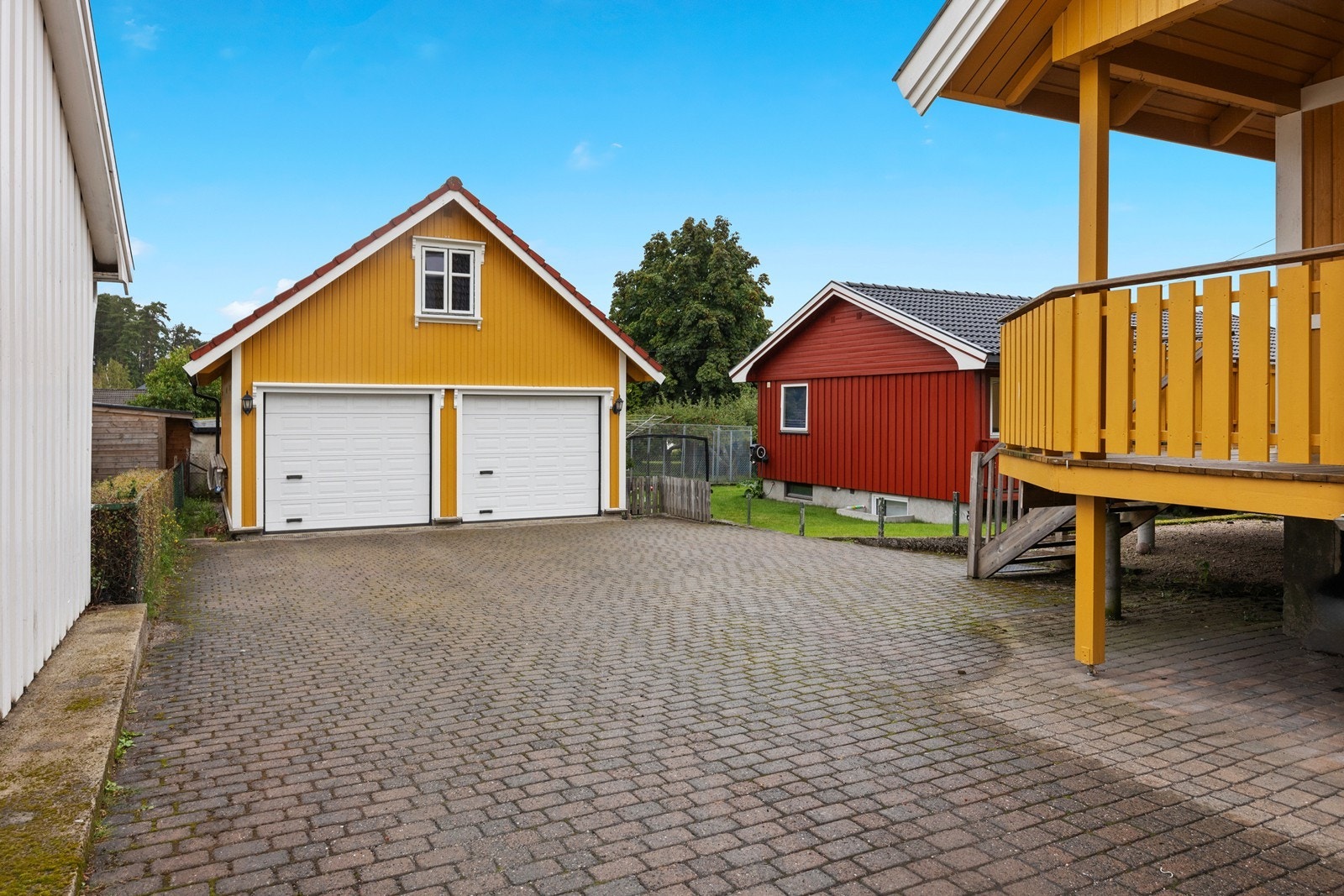 Innkjørsel og gårdsplass er steinlagt - i tillegg er det parkering for to biler i dobbelgarasje, hvor det også er lagringplass Galleribilde