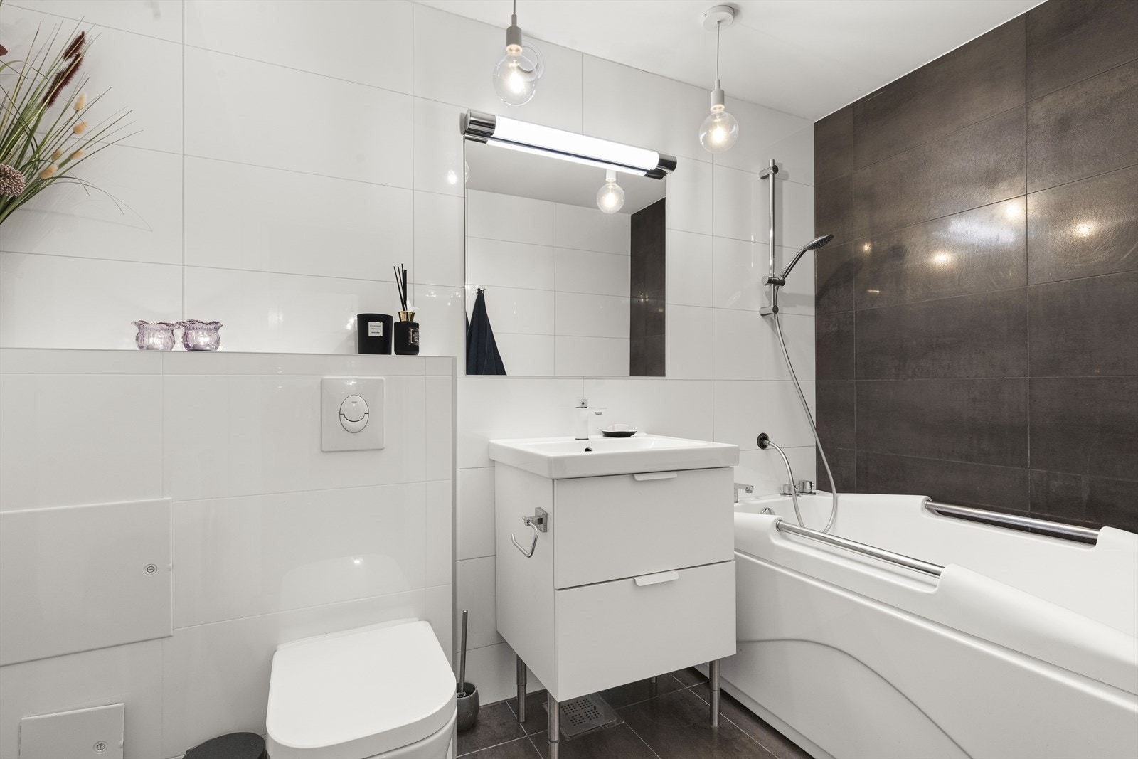 Pent flislagt baderom. Badet har skuffeseksjon med servant, badekar og vegghengt toalett. Galleribilde