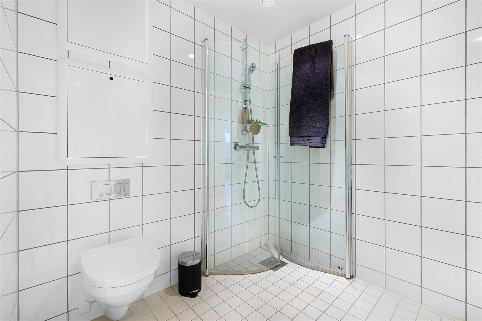 Det er fliset bad med hvite moderne fliser på gulv og vegg. Galleribilde