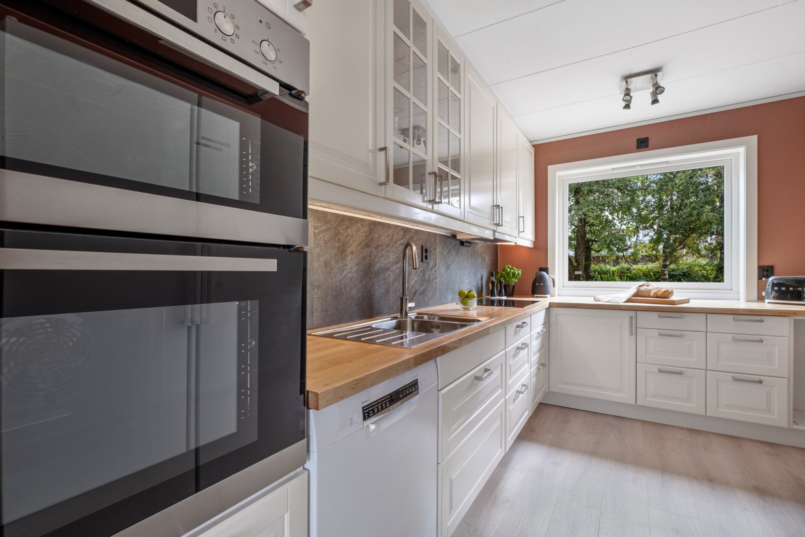 Hvite profilerte fronter og heltre eik benkeplate. Kitchenboard på vegg over benk. Varme i gulv. Galleribilde