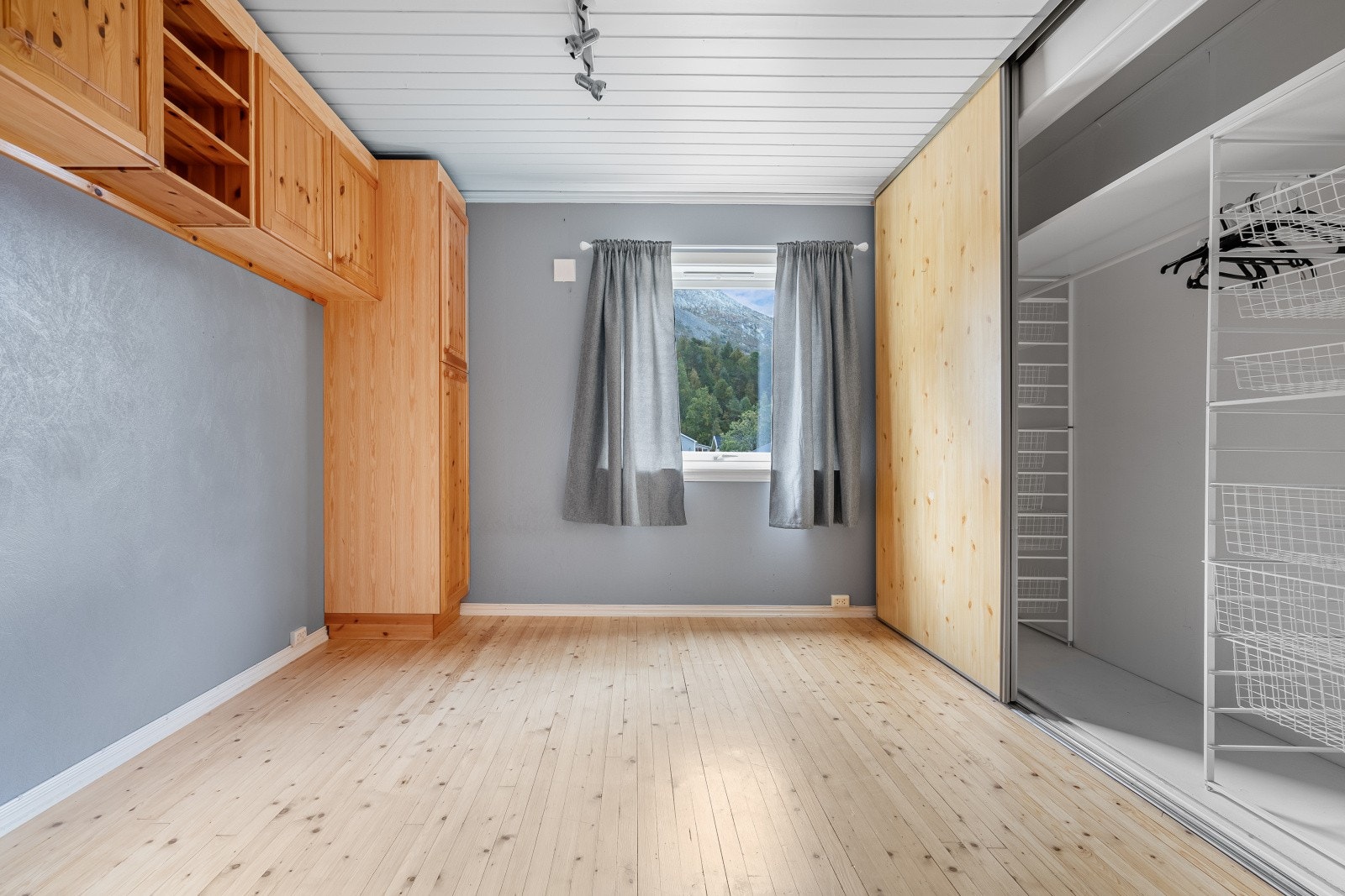 Soverom I - Det er rikelig plass til klesoppbevaring med skyvedørsgarderobe, garderobeskap og vegghengte hyller Galleribilde