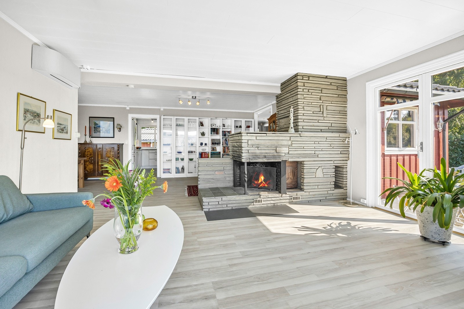 Sentralt i rommet er det stor og lekker peis, og det er i tillegg varmepumpe på veggen. Galleribilde