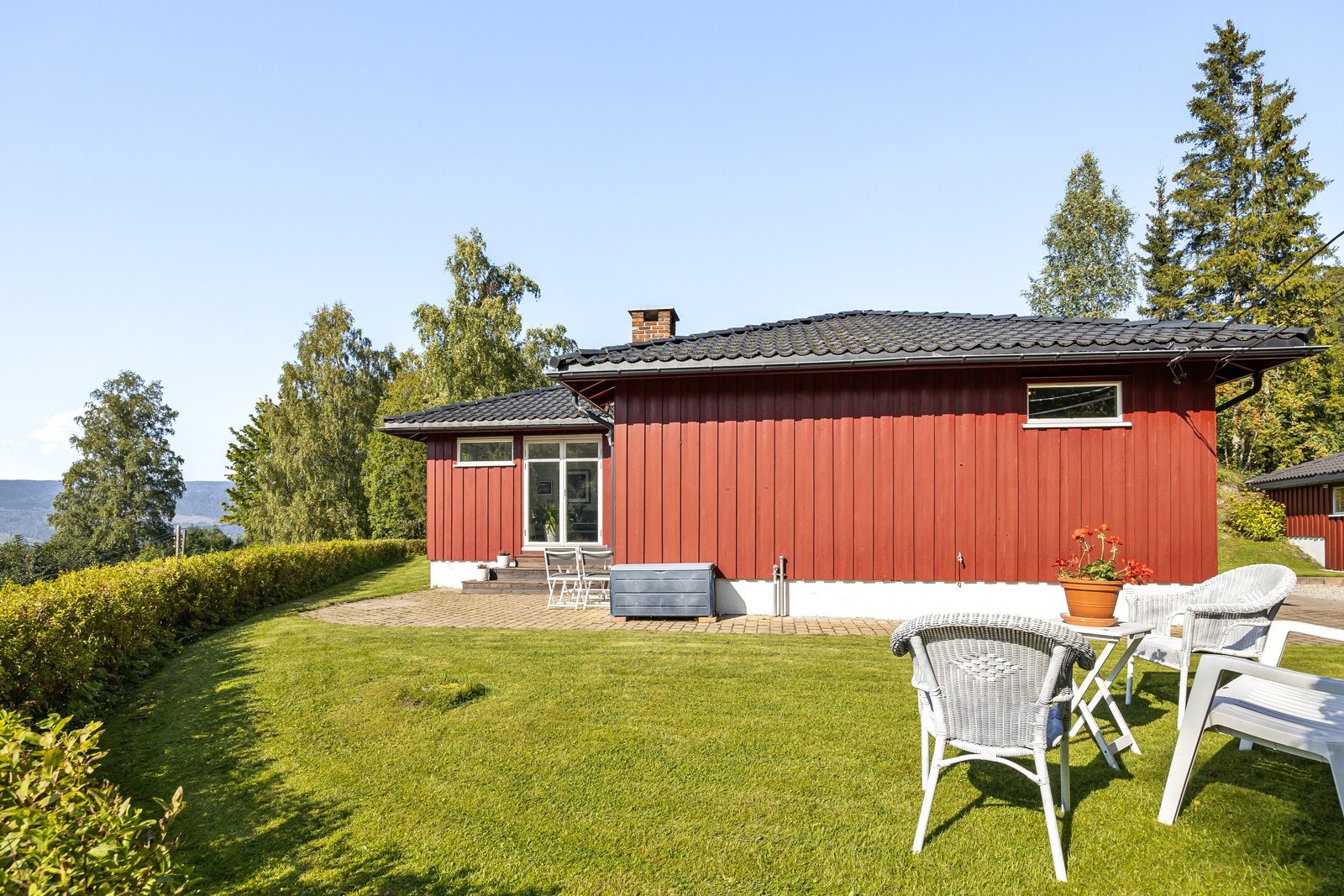 Pent opparbeidet uteområde med stor gressplen, vestvendt terrasse og steinlagt platting. Galleribilde