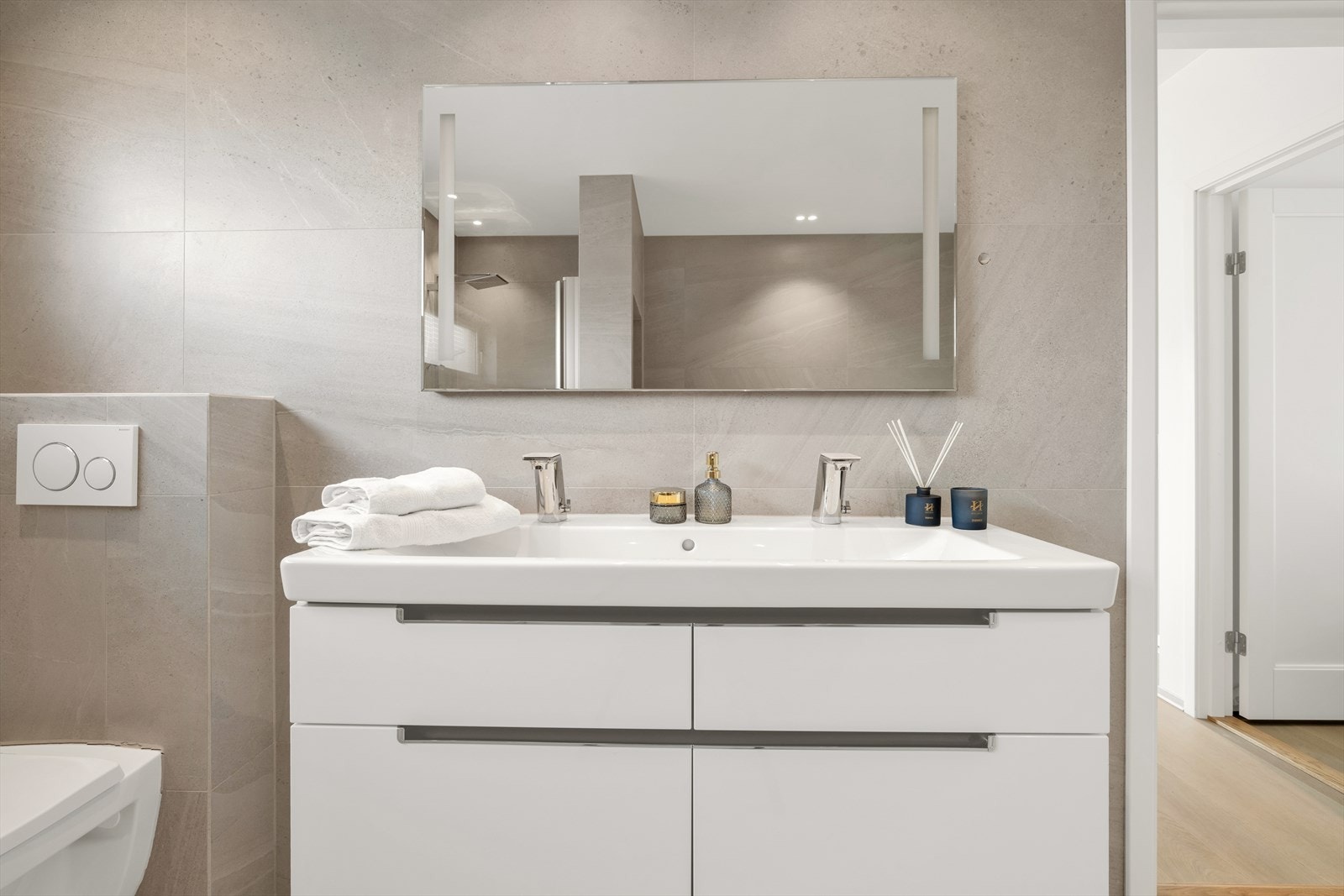 Dobbel servant med overhengt speil og lys, dusj samt vegghengt toalett. Galleribilde